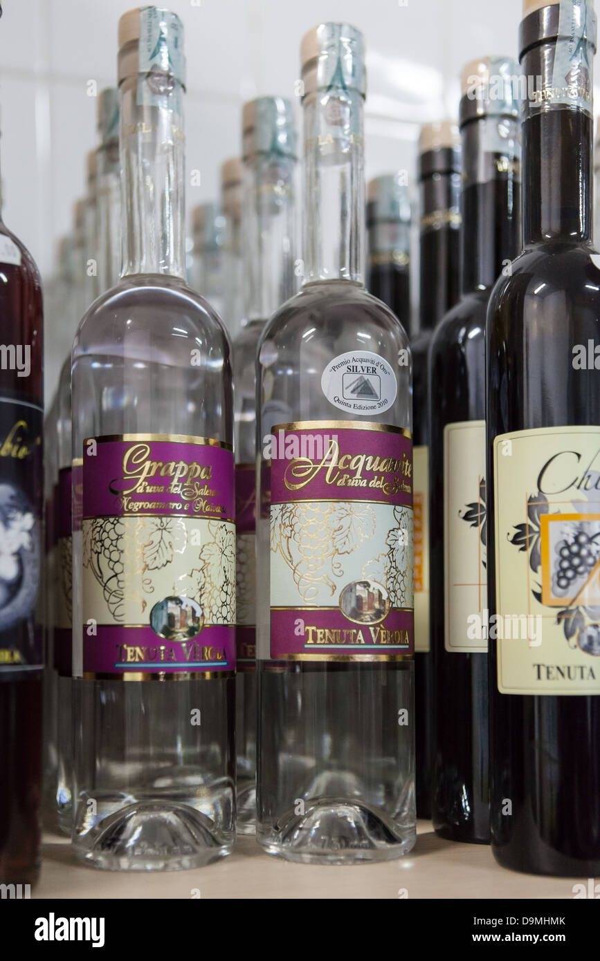 Botellas de vino y aguardientes en los estantes de una salida de fábrica cerca de Lecce, Italia. Foto de stock