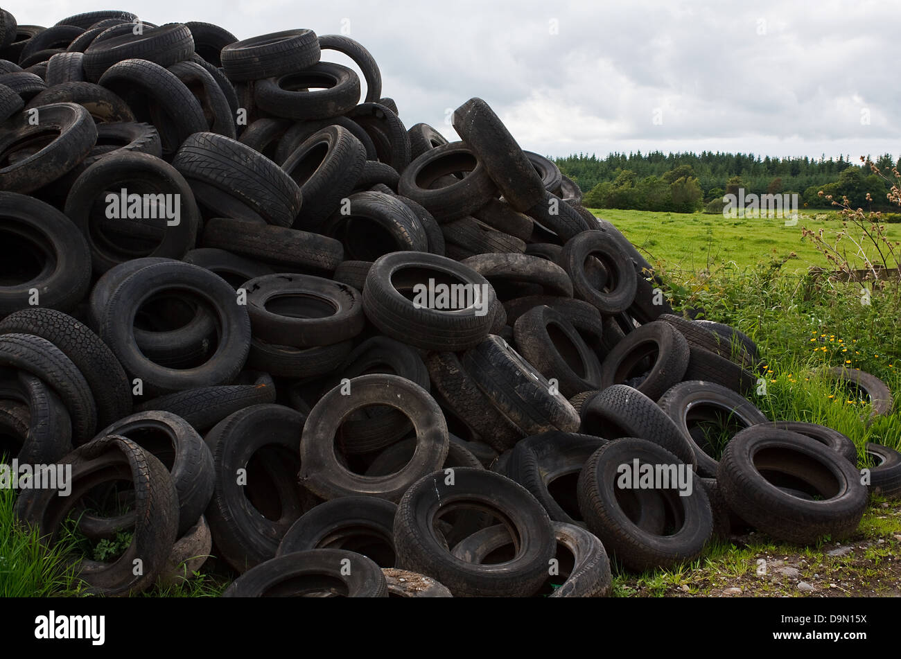 Montón de viejos neumáticos del vehículo tirado en el campo por el agricultor Foto de stock
