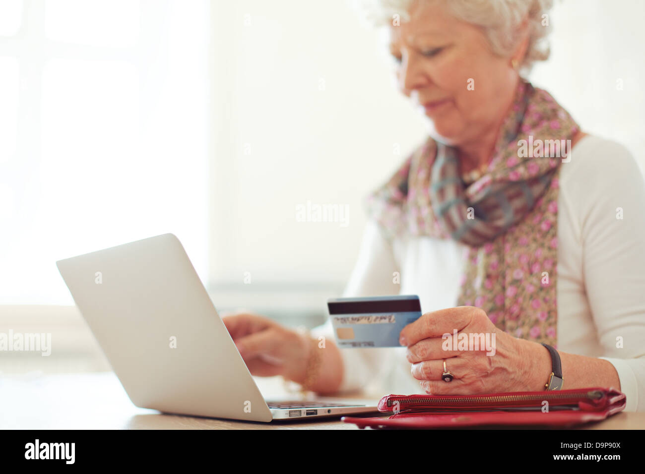 Abuela utilizando una tarjeta de crédito para hacer una transacción en línea Foto de stock