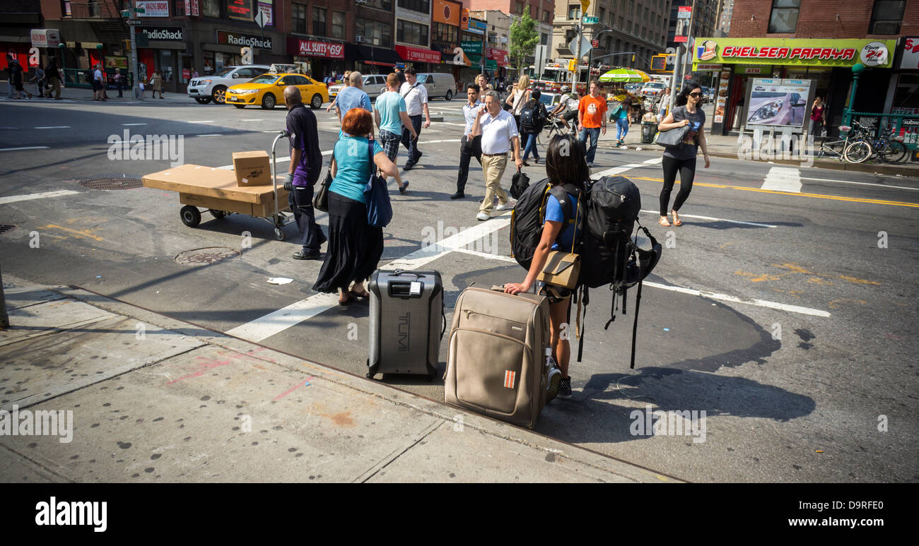 Un viajero cargado con su equipaje, espera un taxi en el barrio de Chelsea,  en Nueva York Fotografía de stock - Alamy