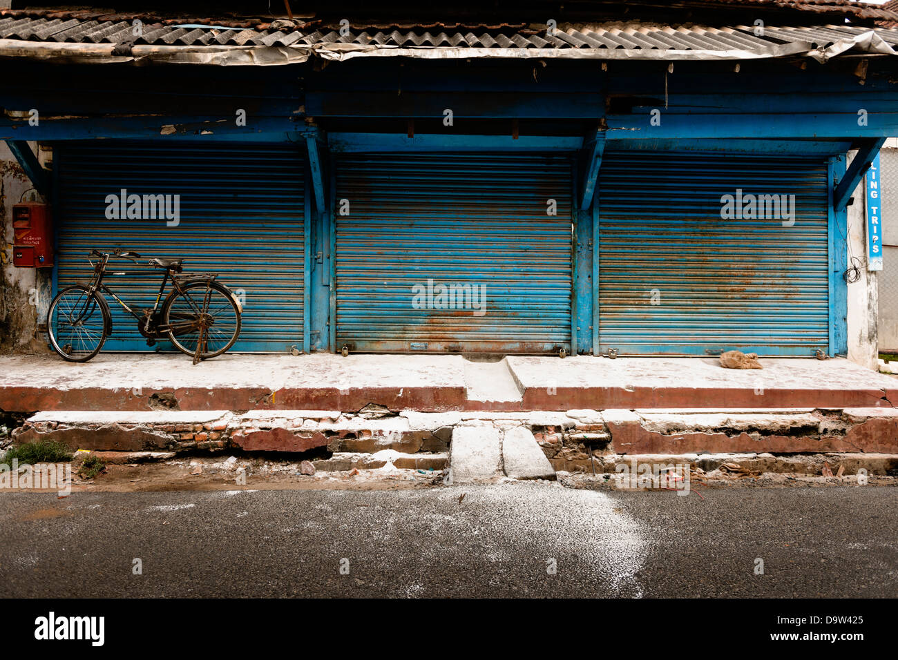 Una bicicleta aparcado fuera de una tienda cerrada en el casco antiguo de la ciudad de Fort Kochi en Kerala, India. Foto de stock