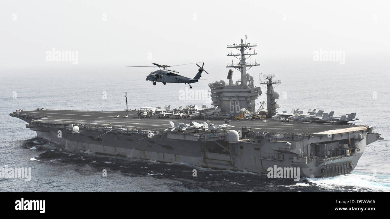 Marina de los EE.UU. MH-60S Sea Hawk helicóptero vuela por el portaaviones USS Nimitz, el 26 de junio de 2013 operan en el Golfo de Omán. Foto de stock