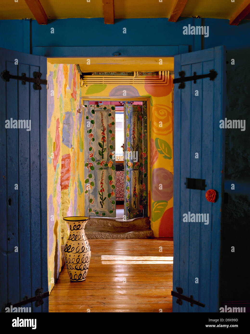 Ver a través de la apertura de puertas azules al tall alfarería jar en el  colorido comedor con suelos de madera y paredes pintadas decorativamente  Fotografía de stock - Alamy