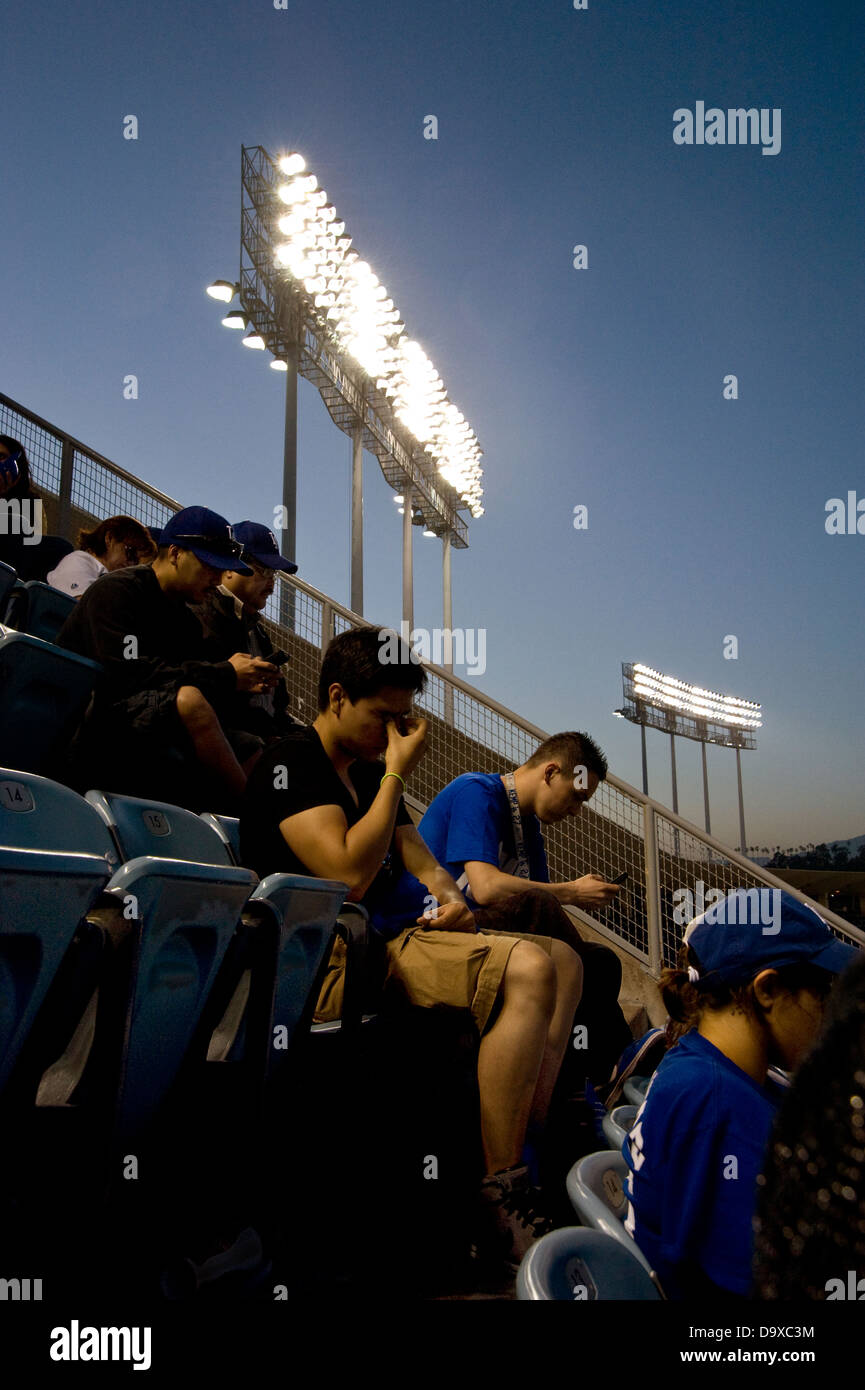 Ventiladores en un evento deportivo usando celulares y mensajes de texto Foto de stock