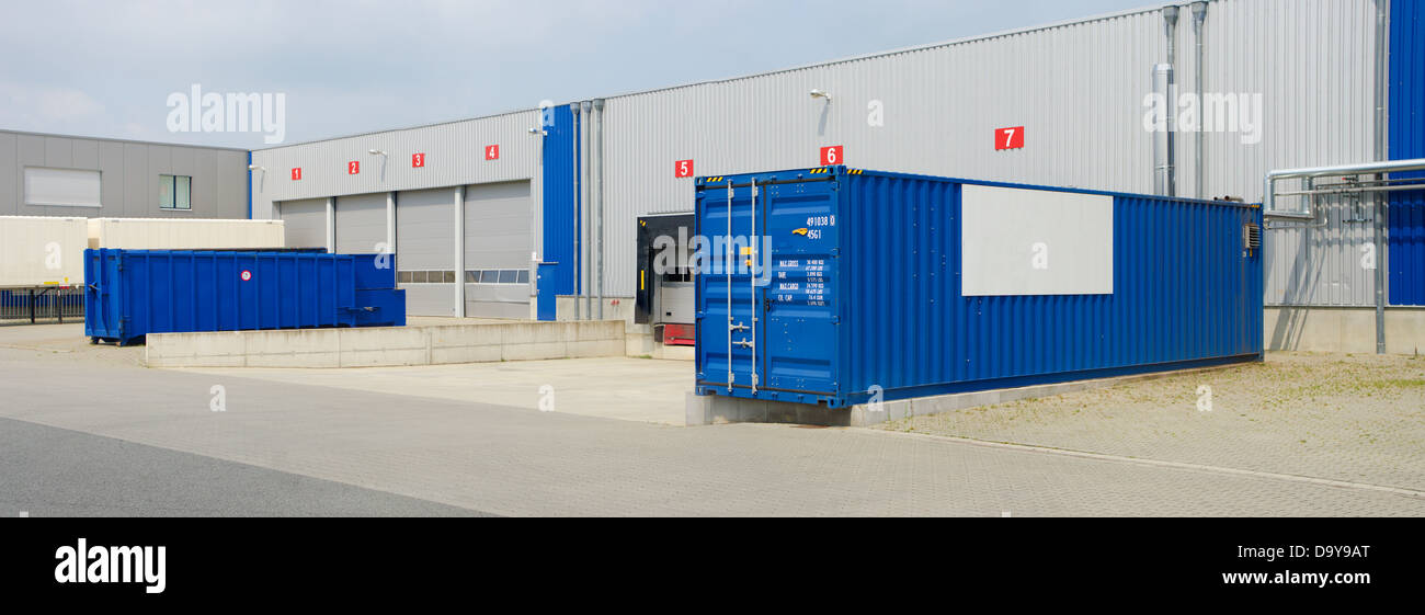 Moderno almacén con contenedores y camiones delante Foto de stock