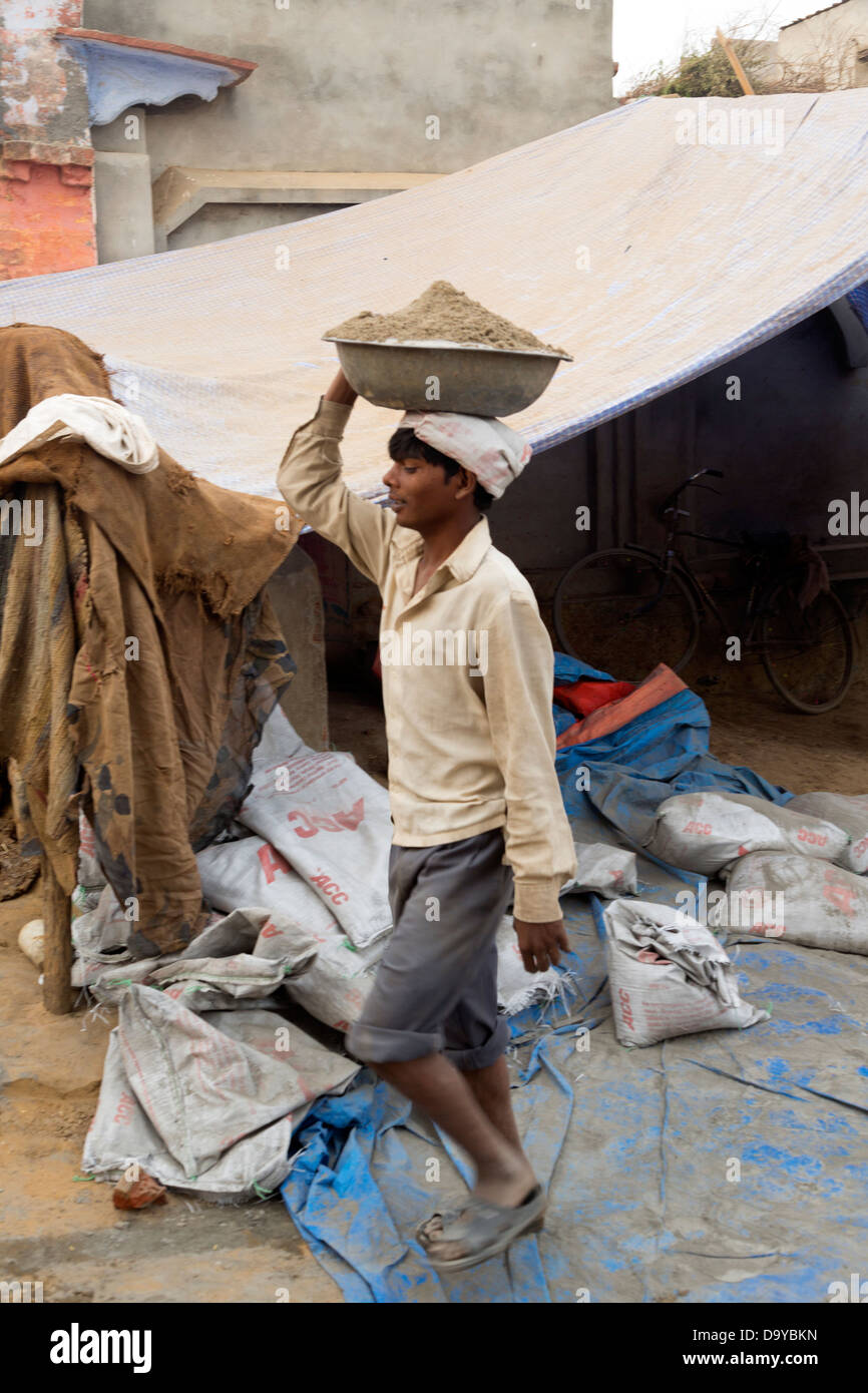 La India, Uttar Pradesh, Aligarh, hombre llevando cemento en tazón Foto de stock