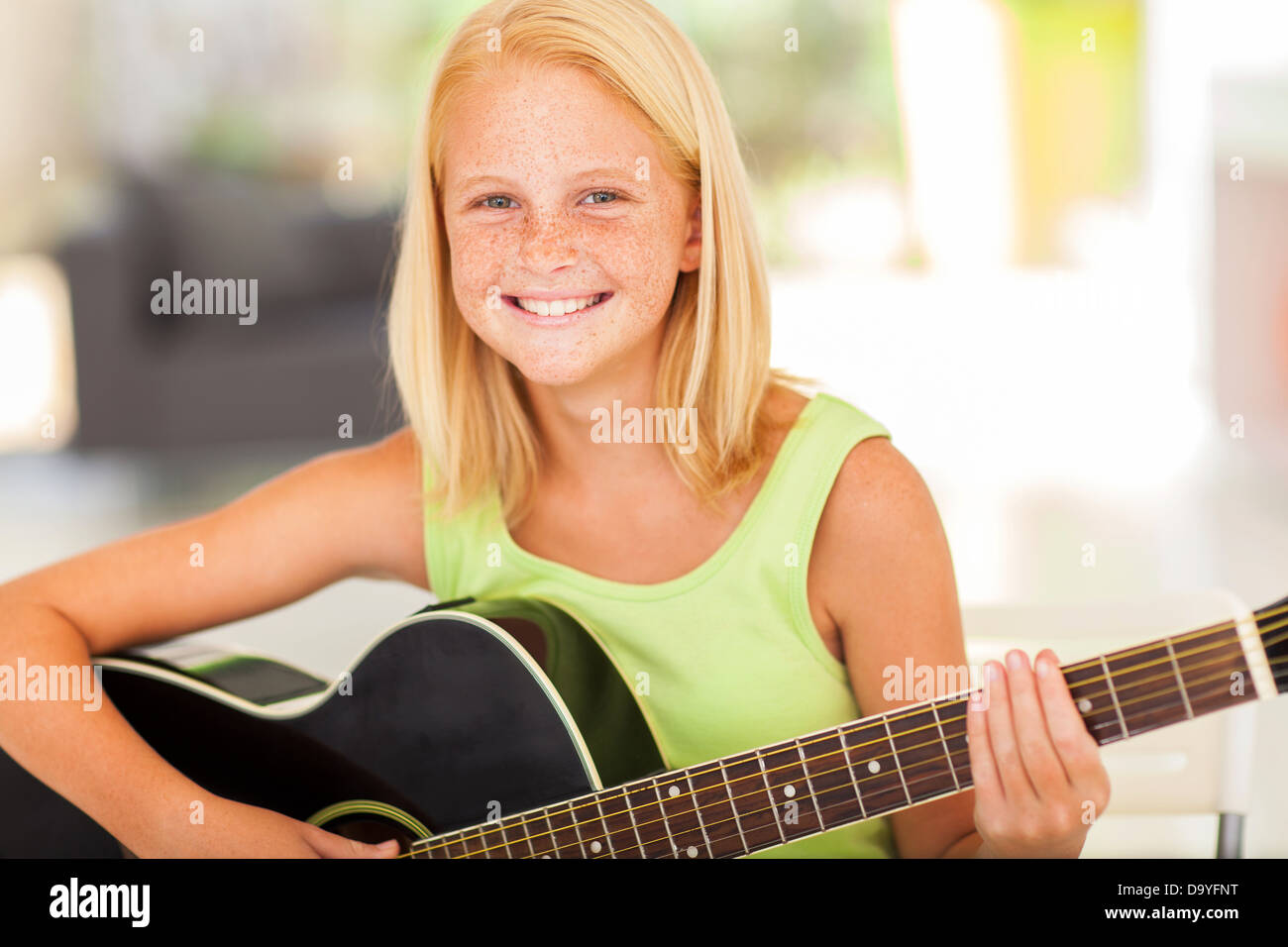 Feliz pre jovencita practicando guitarra en casa Foto de stock