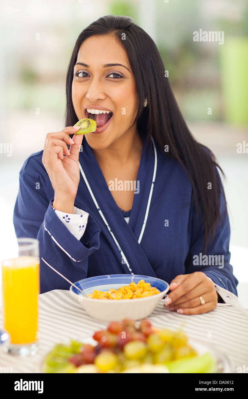 Bonita mujer india comer kiwis durante el desayuno Foto de stock