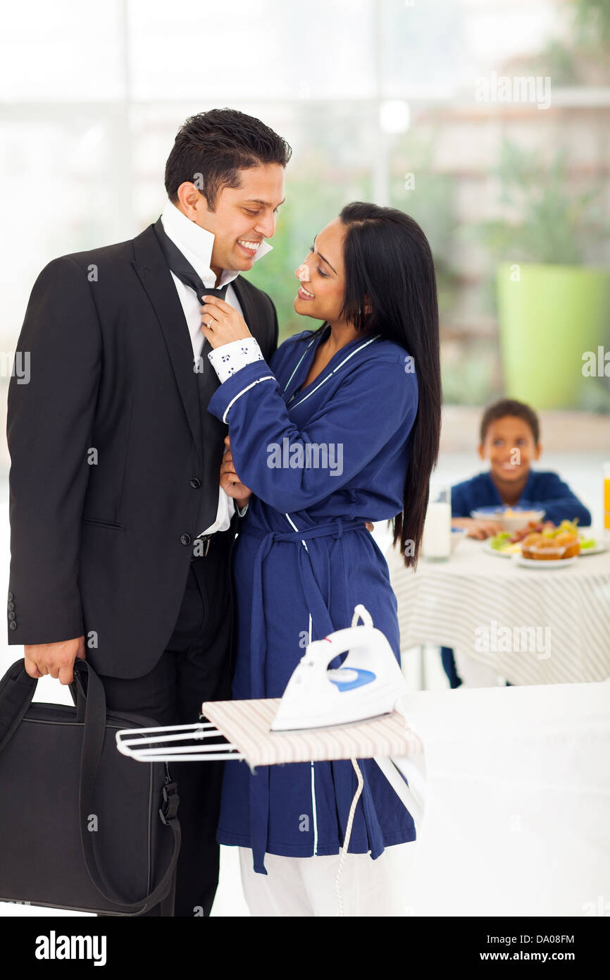 Esposa cariñosa ayudando esposo con su corbata antes de ir a trabajar Foto de stock