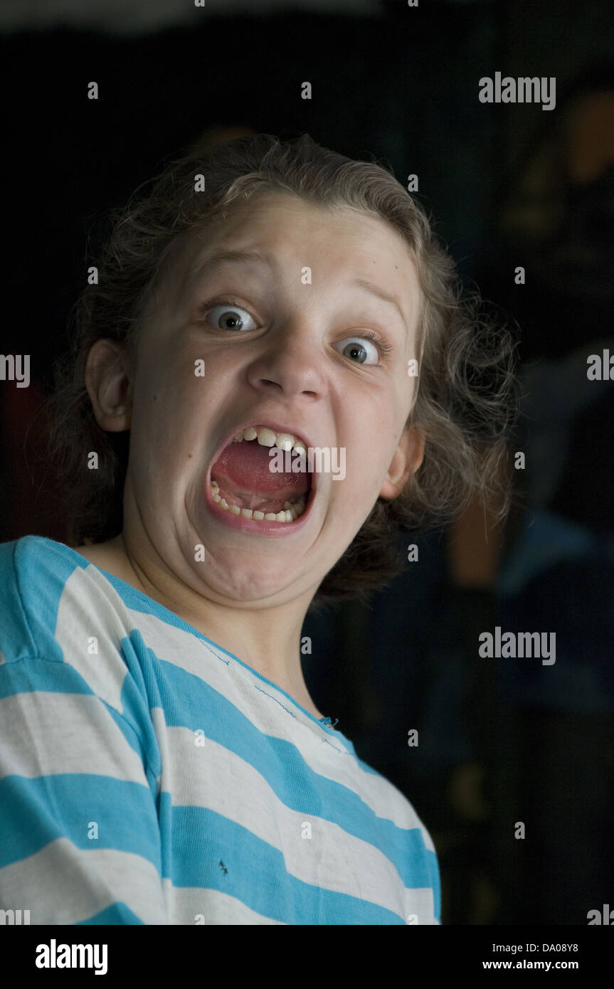 Retrato de una joven gritando con los ojos saltones y azul-blanco camiseta pelado Foto de stock
