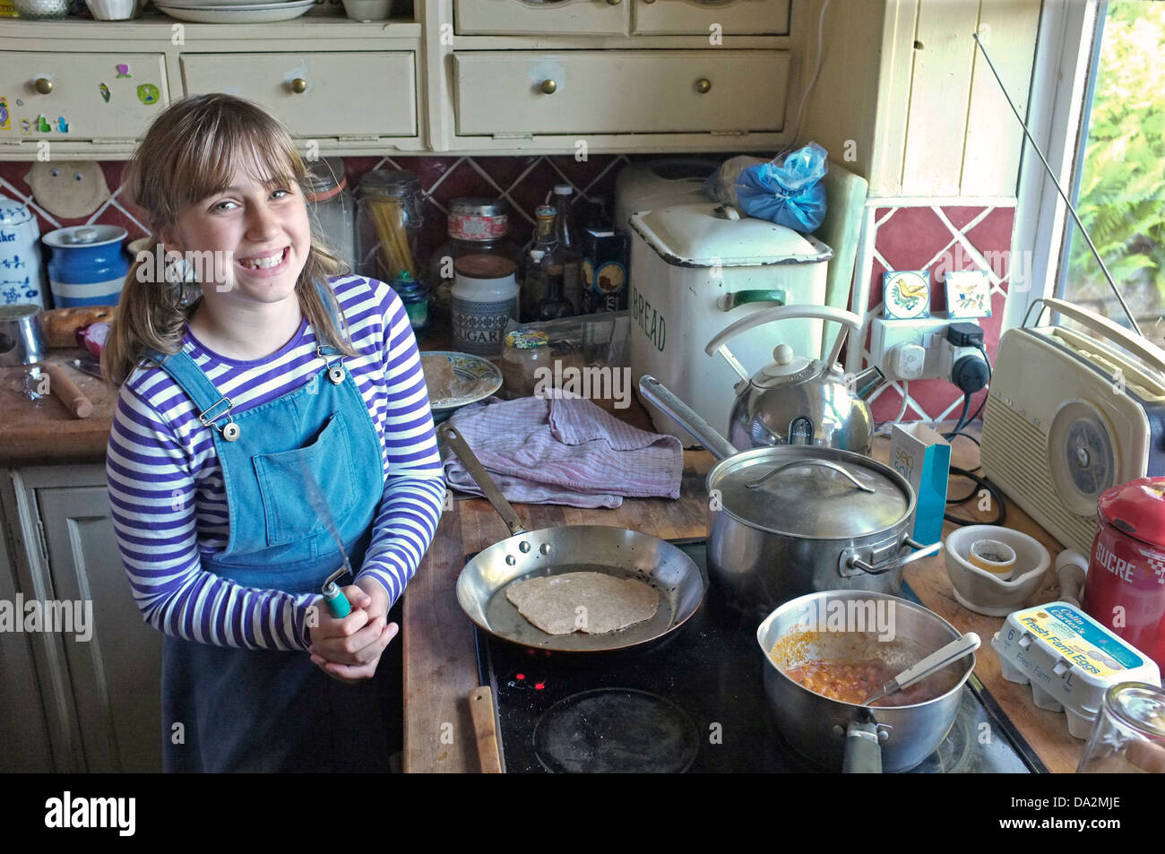 Una niña de 10 años aprendiendo a cocinar chapatis y garbanzos al curry. Foto de stock