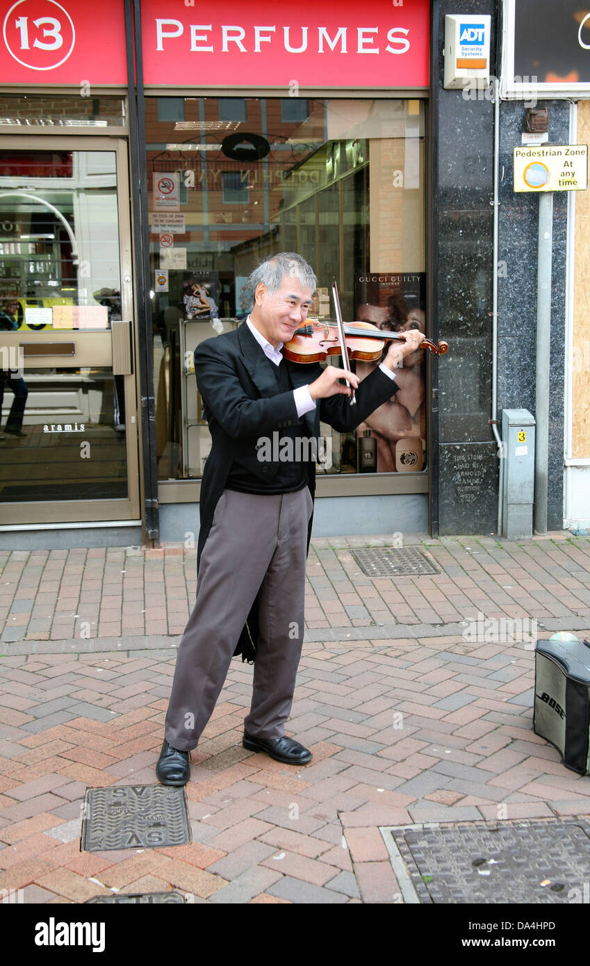 Músico callejero chino con cabello gris a tocar el violín en Hertford Mercado, Hertfordshire, Reino Unido Foto de stock