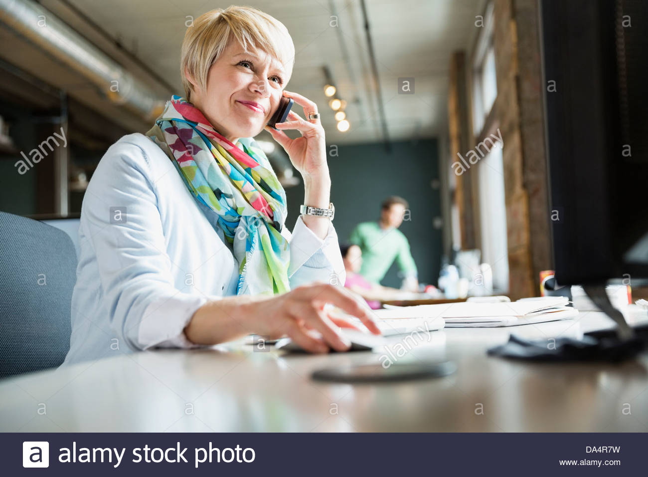 Emprendedor femenino a través de teléfono móvil en el escritorio Foto de stock