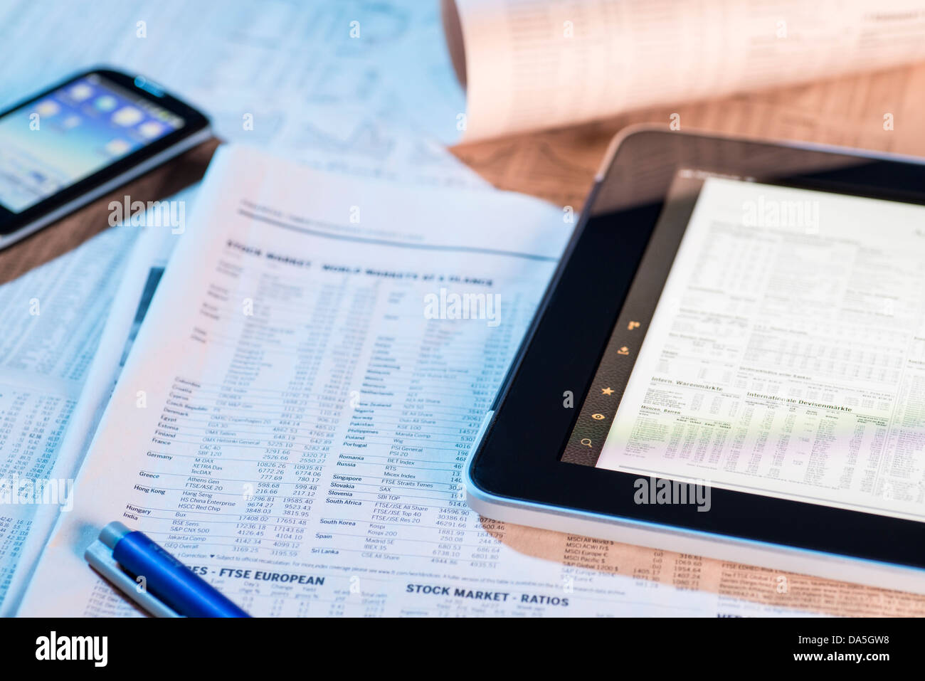 Los precios de las acciones en el periódico y en la pantalla de un equipo tablet PC. Foto de stock