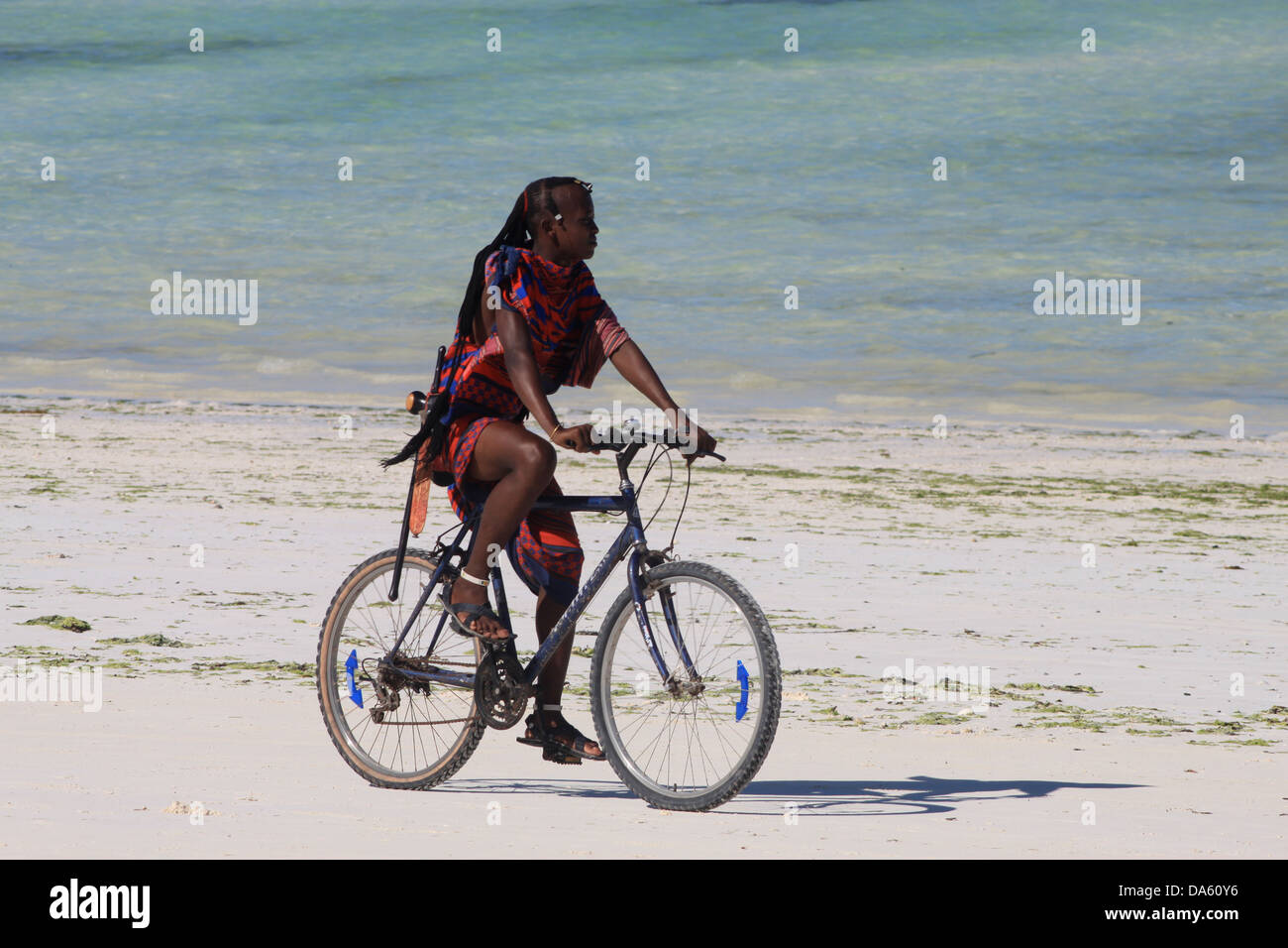 Massai andar en bicicleta en una playa de la Costa Oriental Zanzibars Foto de stock