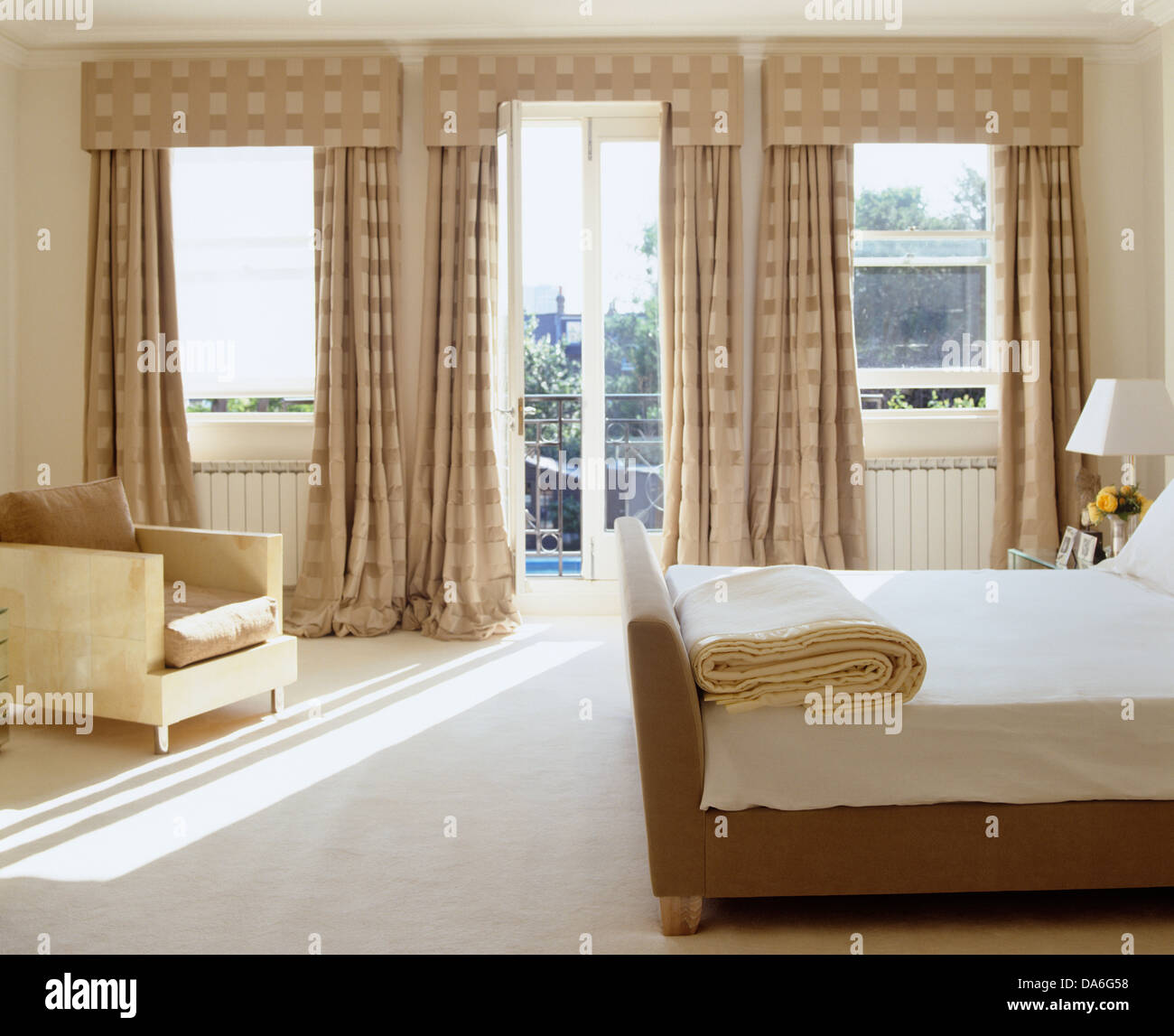 Cama doble y alfombra blanca en dormitorio contemporáneo con suntuosas  cortinas de seda y pelmets beige Fotografía de stock - Alamy