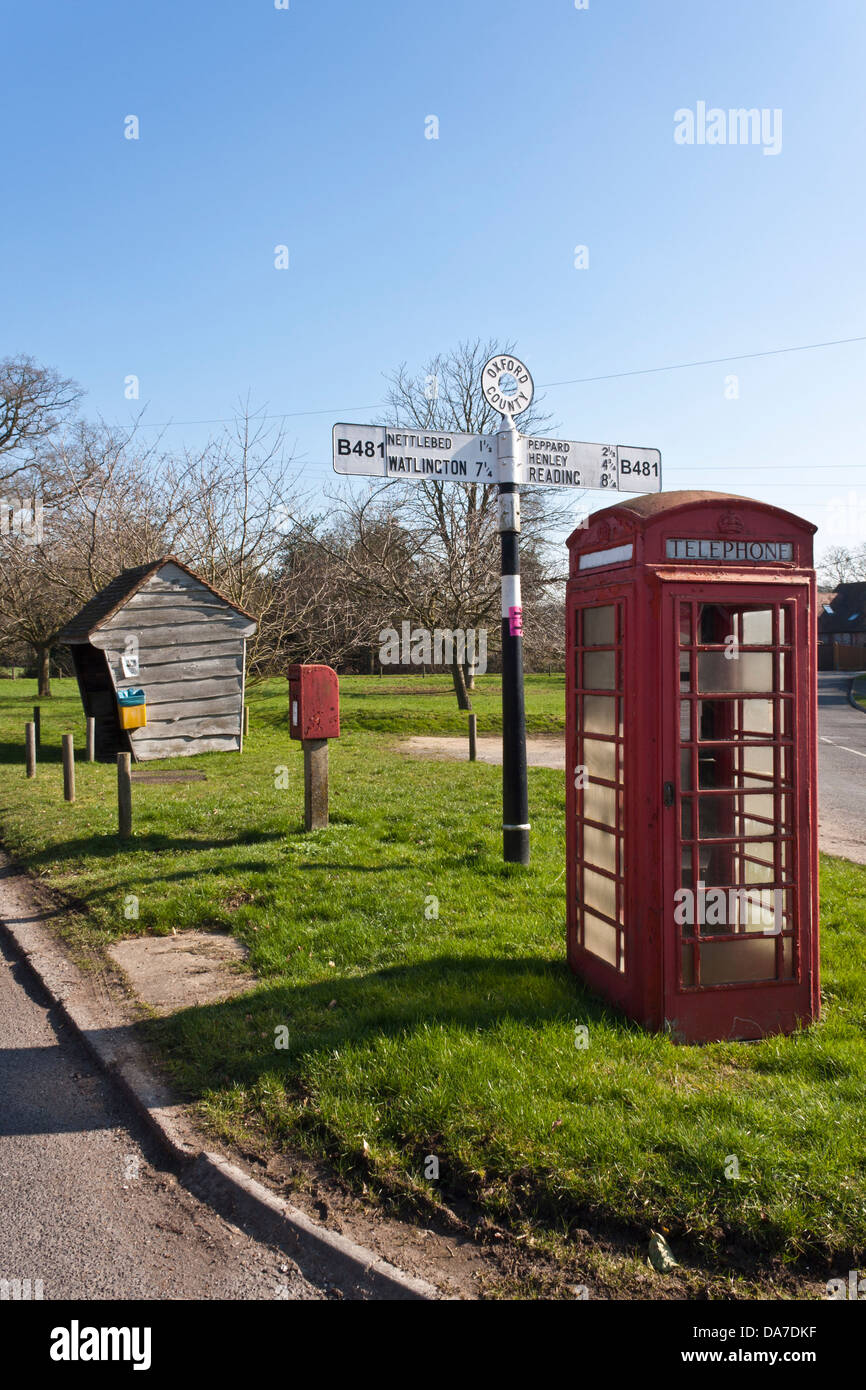 Parada de autobús y de la vivienda, casilla postal, teléfono y caja de señales de carretera sobre la hierba. Cruz Highmoor, Oxfordshire, Inglaterra, GB, Reino Unido. Foto de stock