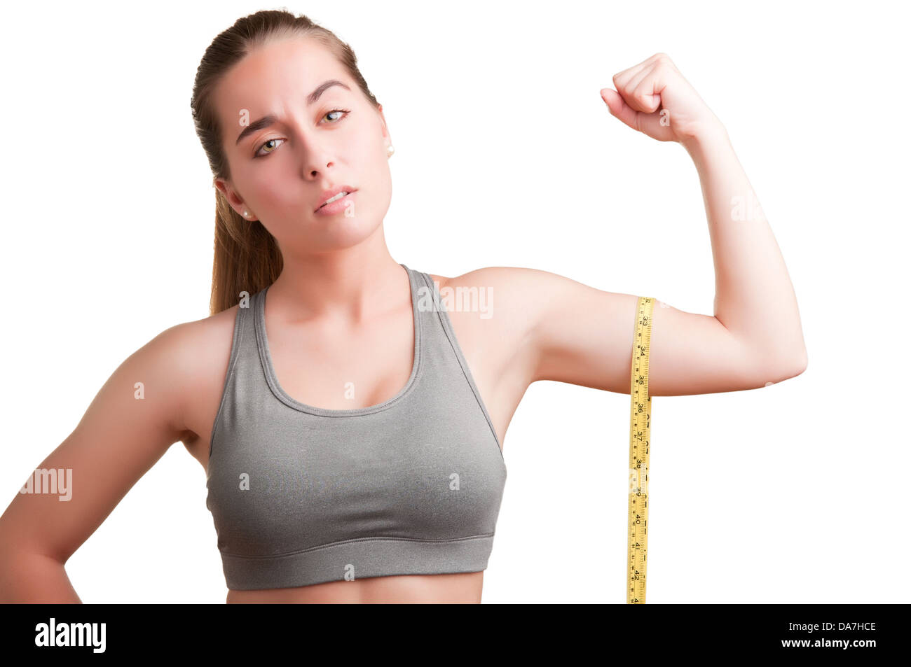 Mujer poderosa midiendo sus bíceps con una cinta de medición amarilla Foto de stock