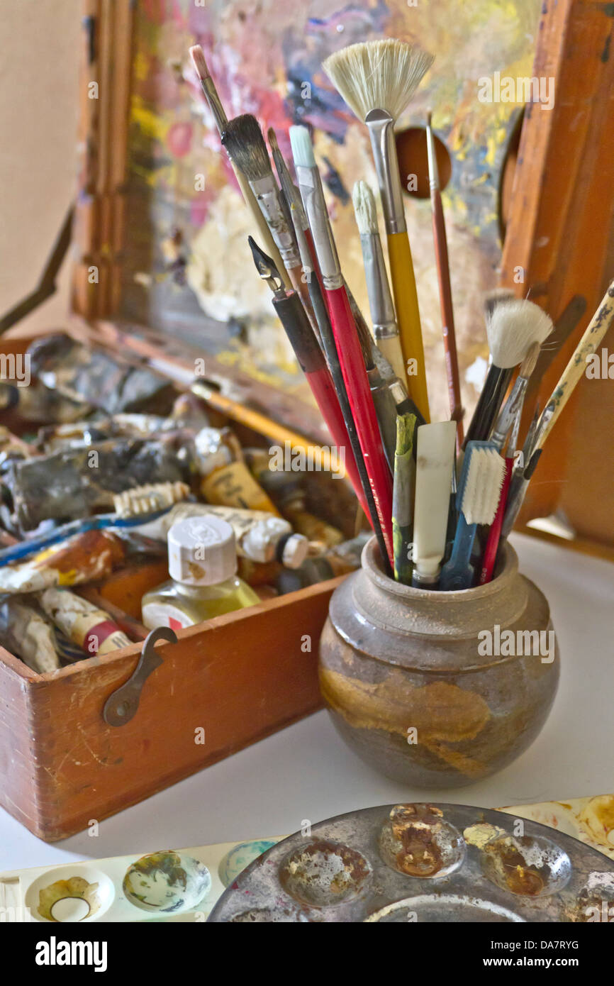 Cerca de pinceles, pinturas del artista, paleta, mezcla de tazas, pen y paintbox Foto de stock