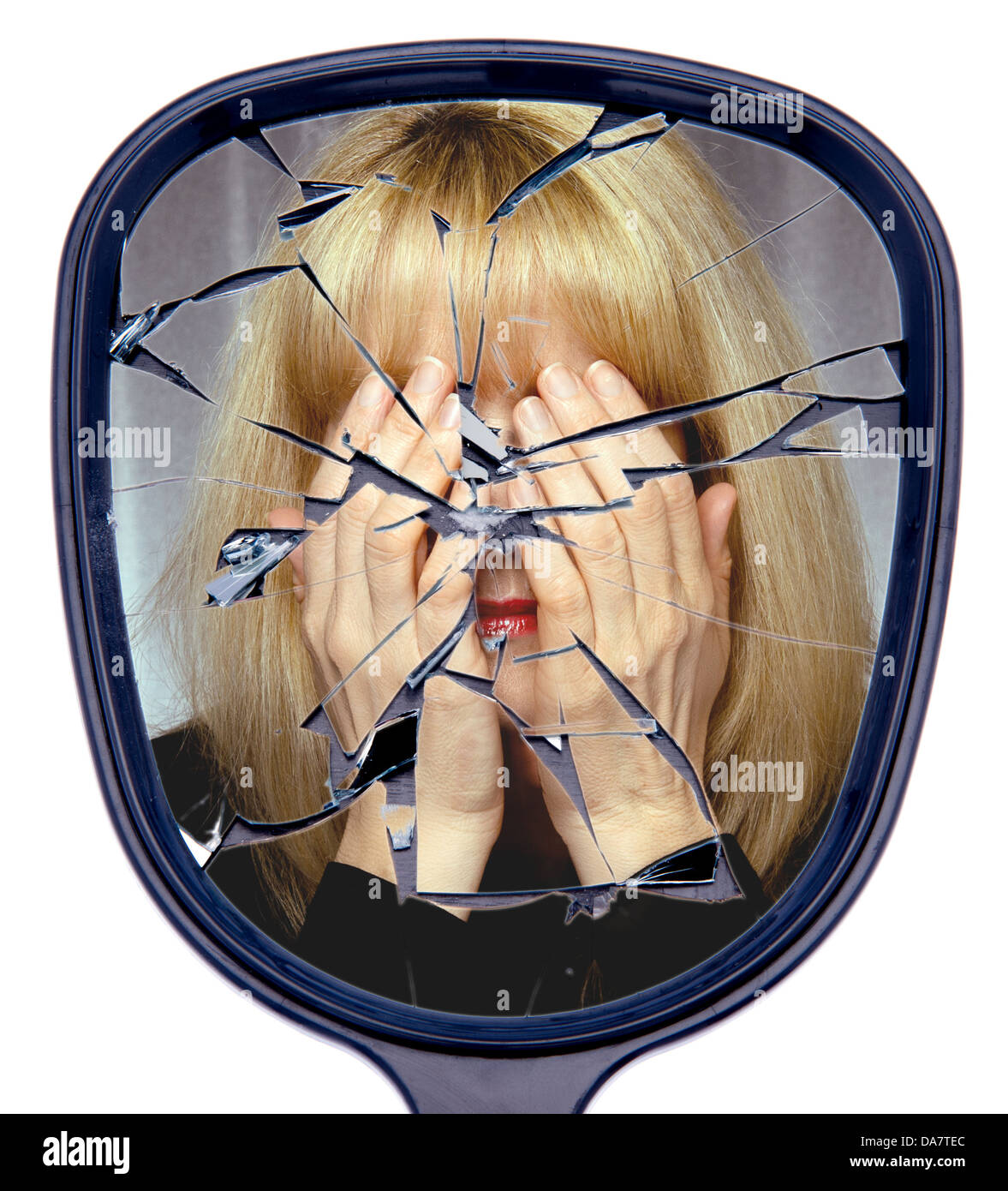 Una mujer cubre su cara reflejada en un espejo roto o el concepto de la vida destrozada Foto de stock