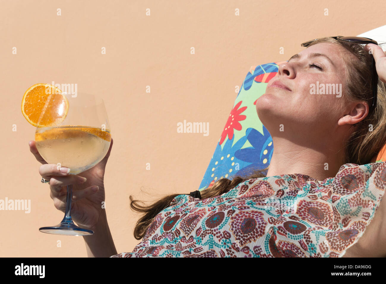 Mujer joven relajarse bajo el sol con una bebida fría. Foto de stock