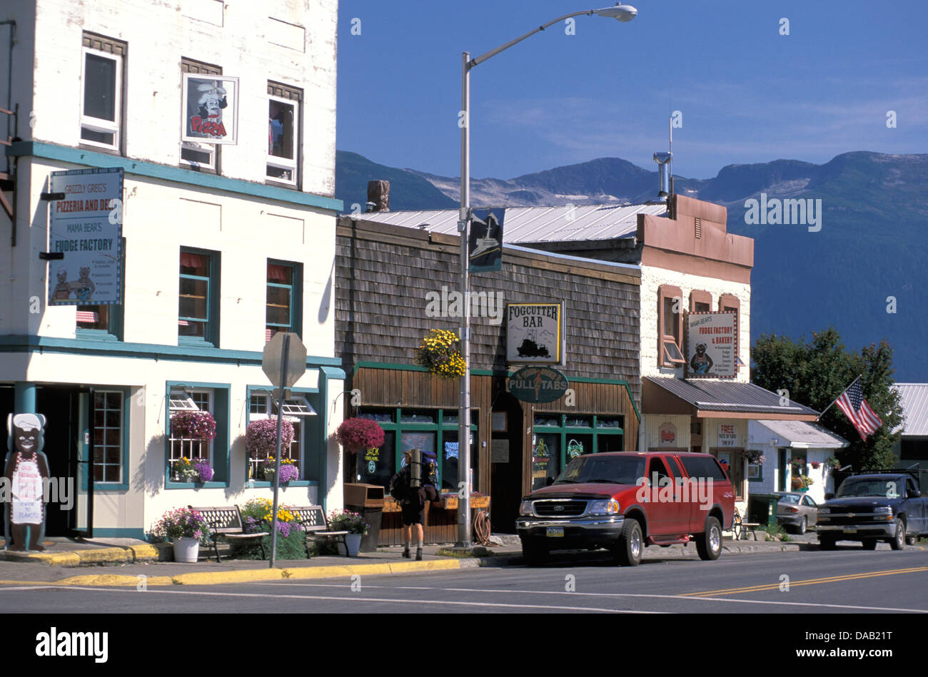 Haines, Alaska, EE.UU., pequeña ciudad, edificios antiguos, soleado, los coches aparcados, flores en macetas, bar, blue sky Foto de stock