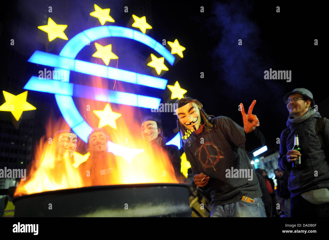 Los manifestantes vestían "máscaras" de Guy Fawkes para estar junto al fuego en frente del Banco Central Europeo en Frankfurt, Alemania, el 15 de octubre de 2011. Varios miles de personas han estado protestando contra el poder de los mercados financieros. Los modelos de circulación en el Americano "ocupar Wall Street" las protestas. Foto: Arne Dedert Foto de stock