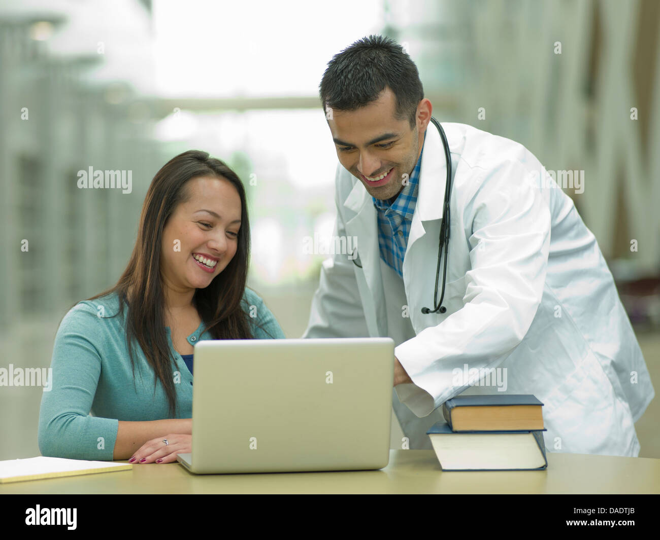 Adulto medio médico con portátil con el joven estudiante, sonriendo Foto de stock
