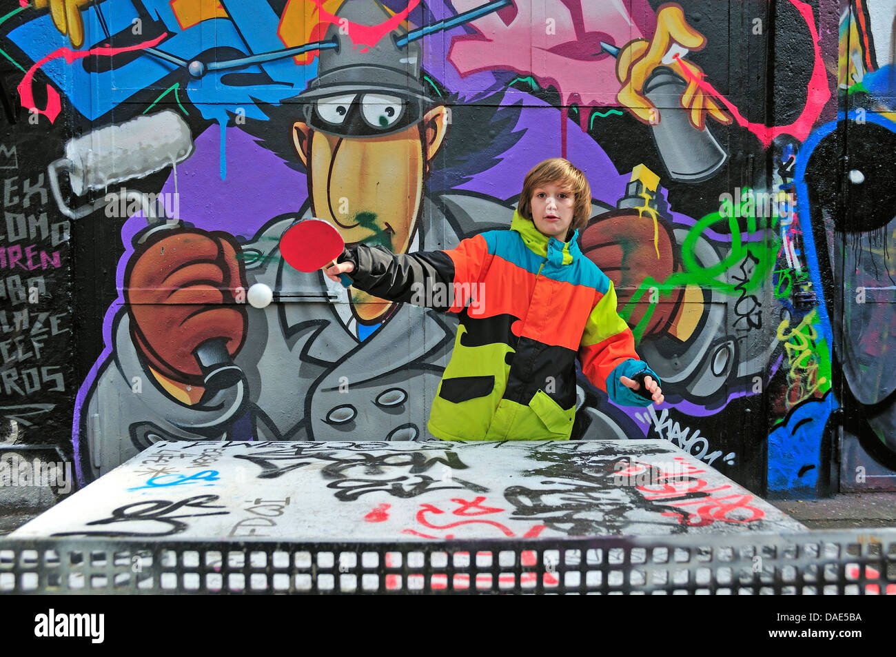 Doce-año-viejo muchacho jugando al tenis de mesa delante de graffiti wall, en Alemania, en Renania del Norte-Westfalia, Colonia Foto de stock