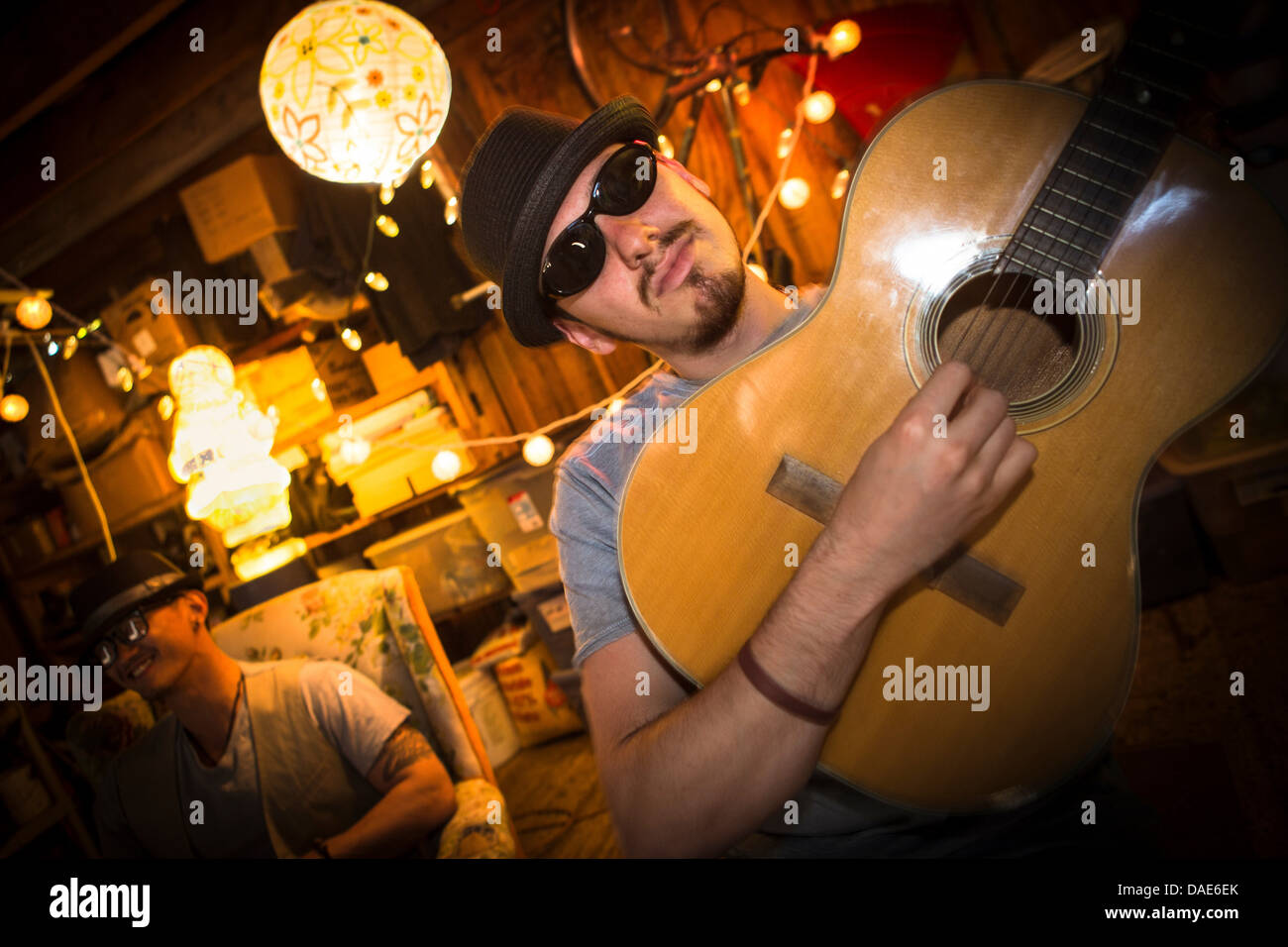 Hombre vestido con gorra y gafas de sol tocando la guitarra Foto de stock