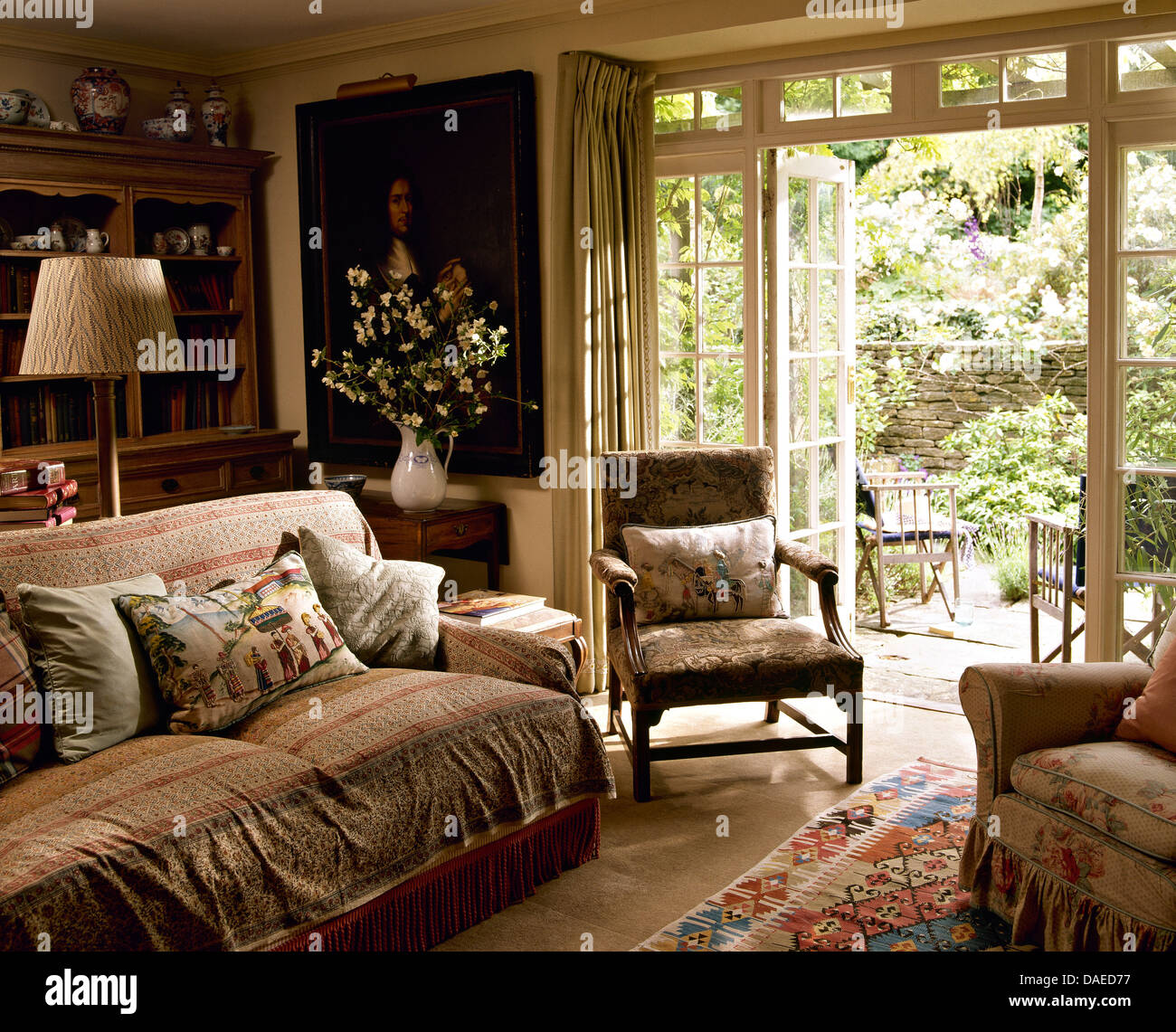 Telas cojines y echar en el sofá en casa Salón con sillón junto a abrir  ventanas francesas para el jardín Fotografía de stock - Alamy