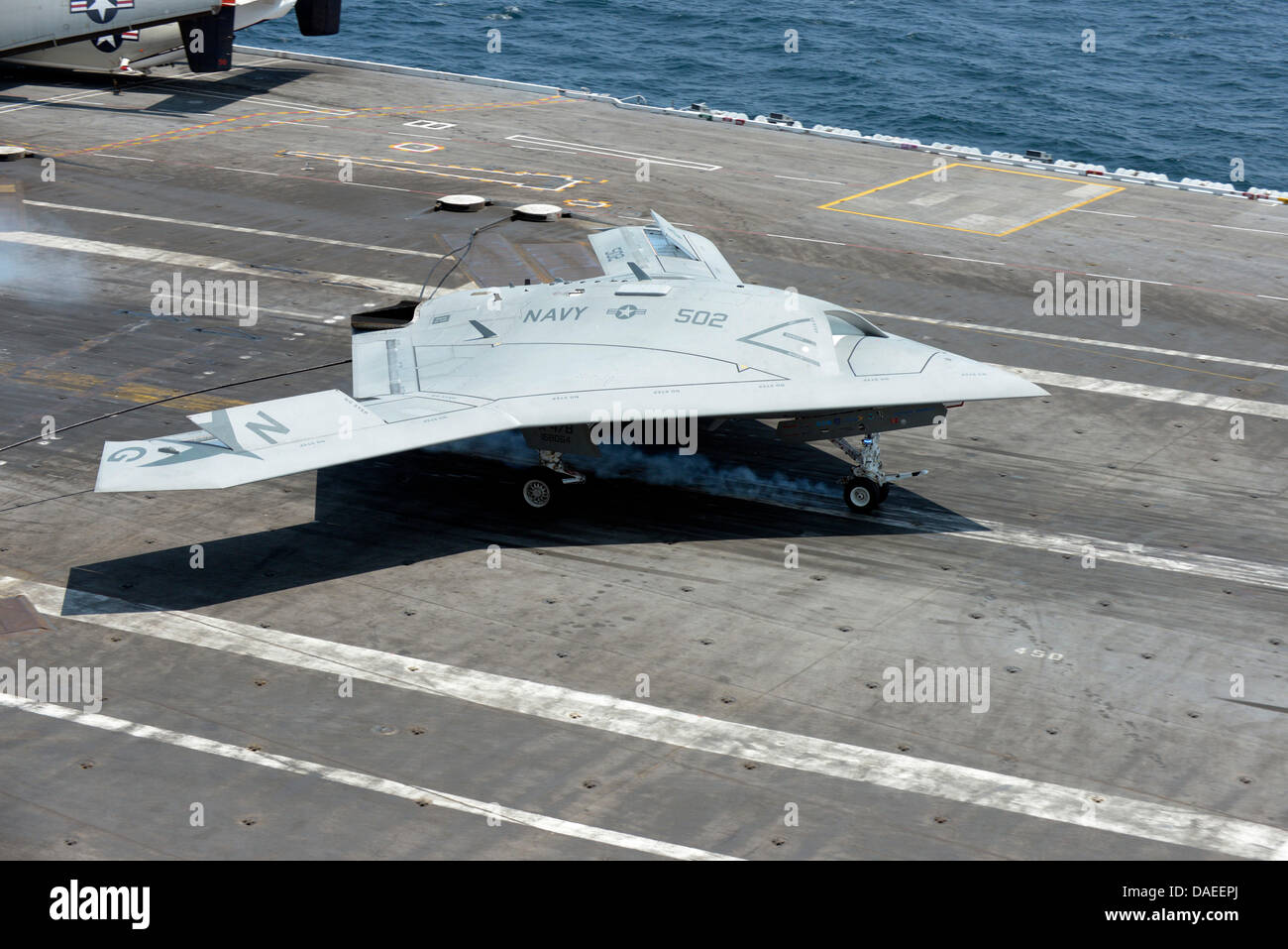 Marina de los EE.UU. X-47B sistema de combate aéreo no tripulado drone detenido hace un aterrizaje en la cubierta de vuelo del portaaviones USS George H.W. Bush el 10 de julio de 2013 operan en el Océano Atlántico. El desembarco marcó la primera vez que una aeronave no tripulada completó un detenido el aterrizaje en el mar. Foto de stock