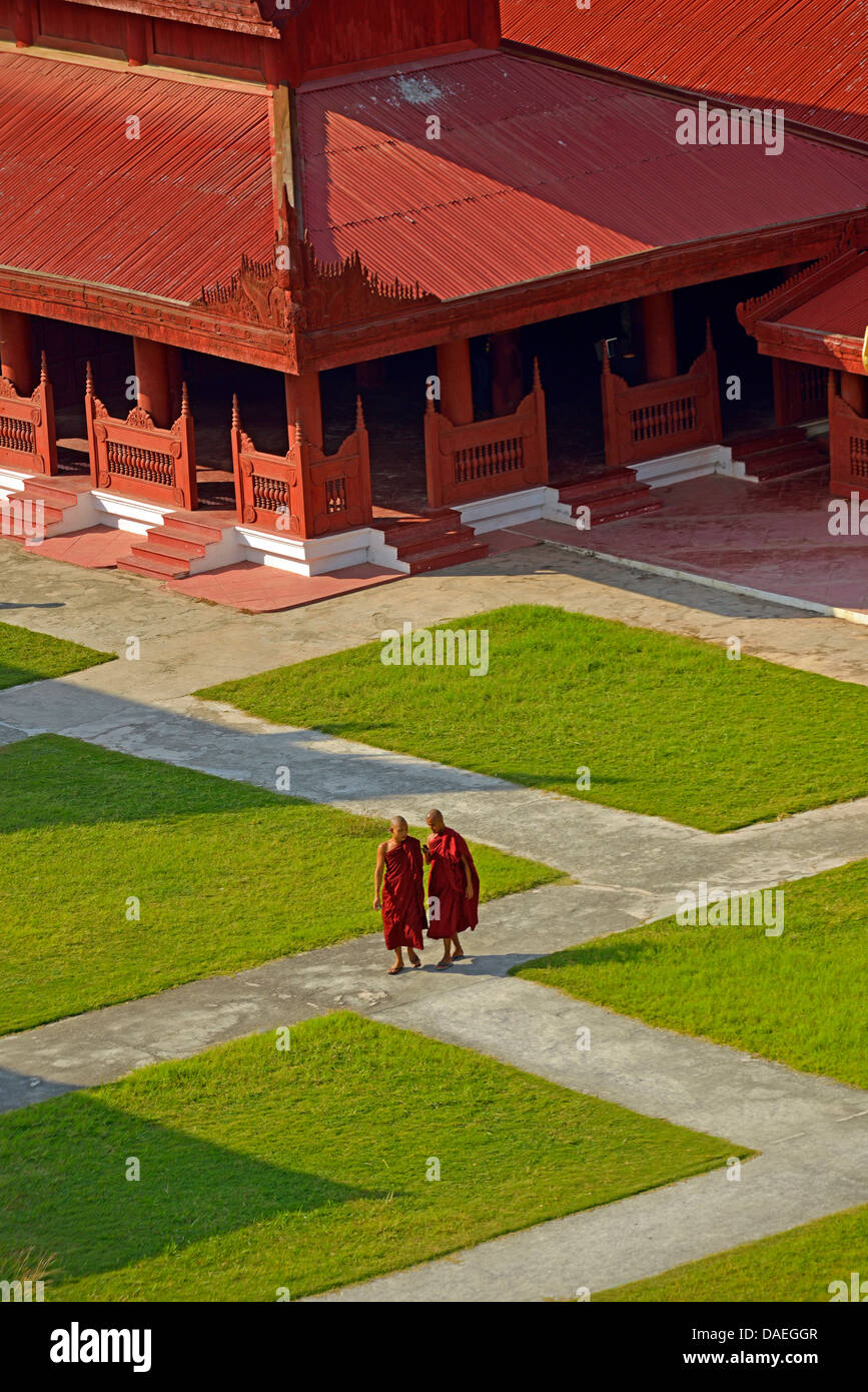 Dos jóvenes monjes caminando por un sendero entre los edificios del Palacio de Mandalay, Birmania, Mandalay Foto de stock