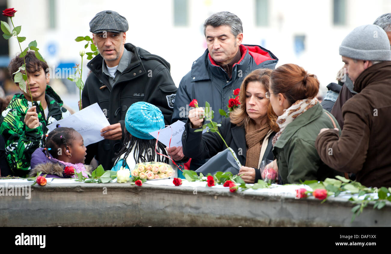 Las personas colocan rosas blancas y rojas junto a los papeles con los nombres de las víctimas de una serie de asesinatos durante una manifestación neonazi y el minuto de silencio, bajo el lema: 'Silencio multitud silenciosa contra el Silencio" en el Geschwister-Scholl-cuadrado en Munich, Alemania, el 26 de noviembre de 2011. A nivel nacional un minuto de silencio se inició en 11 ciudades en Alemania por la asociación TypischDeuts Foto de stock