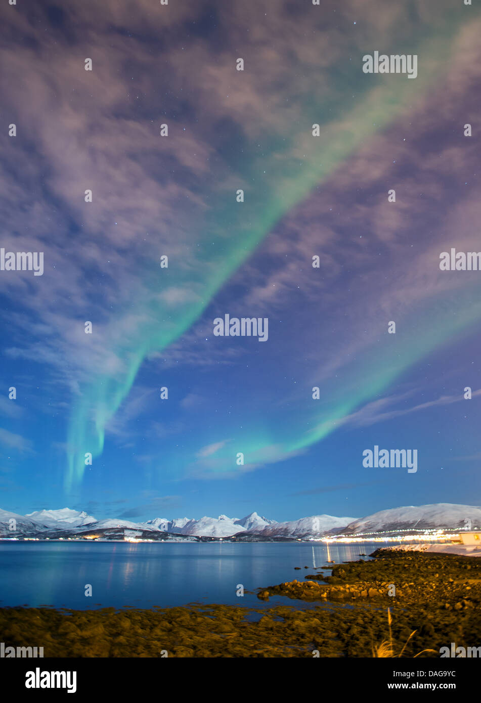 Aurora en frente de nubes y el cielo estrellado durante los techos cubiertos  de nieve de una urbanización en el SONIDO DE SANDNES, NORUEGA Troms,  Kvaloeya, Tromsoe Fotografía de stock - Alamy