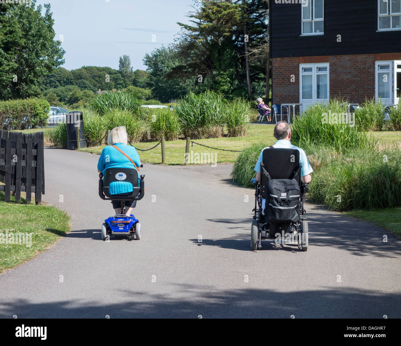 Pareja de jubilados Elderley sobre movilidad y sillas de ruedas Scooter Foto de stock