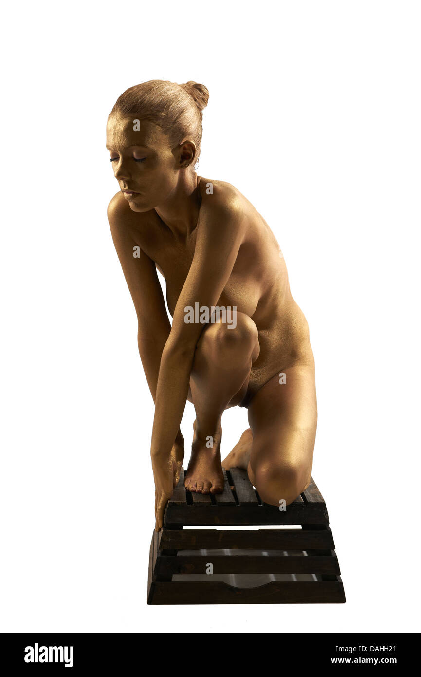 Joven mujer desnuda pintada en oro posando Fotografía de stock - Alamy