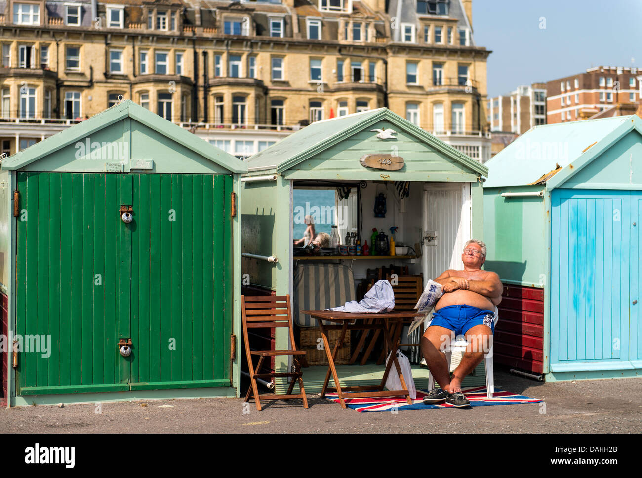Viejo disfrutando del sol por cabañas de playa en Brighton, Inglaterra Gran Bretaña UK Foto de stock