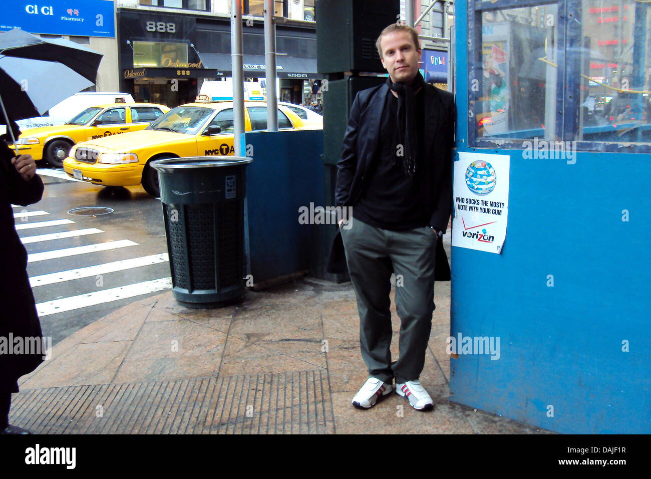 El artista Alemán Stefan Haferkamp posa junto a un cartel de la compañía telefónica Verizon en la 6ª Avenida en Nueva York, Estados Unidos, 11 de abril de 2011. La calle-arte-campaña de Haferkamp invita al espectador a escupir sobre los carteles de la detestaron empresas telefónicas con gomas de mascar. Foto: Benedikt S. Scheper Foto de stock