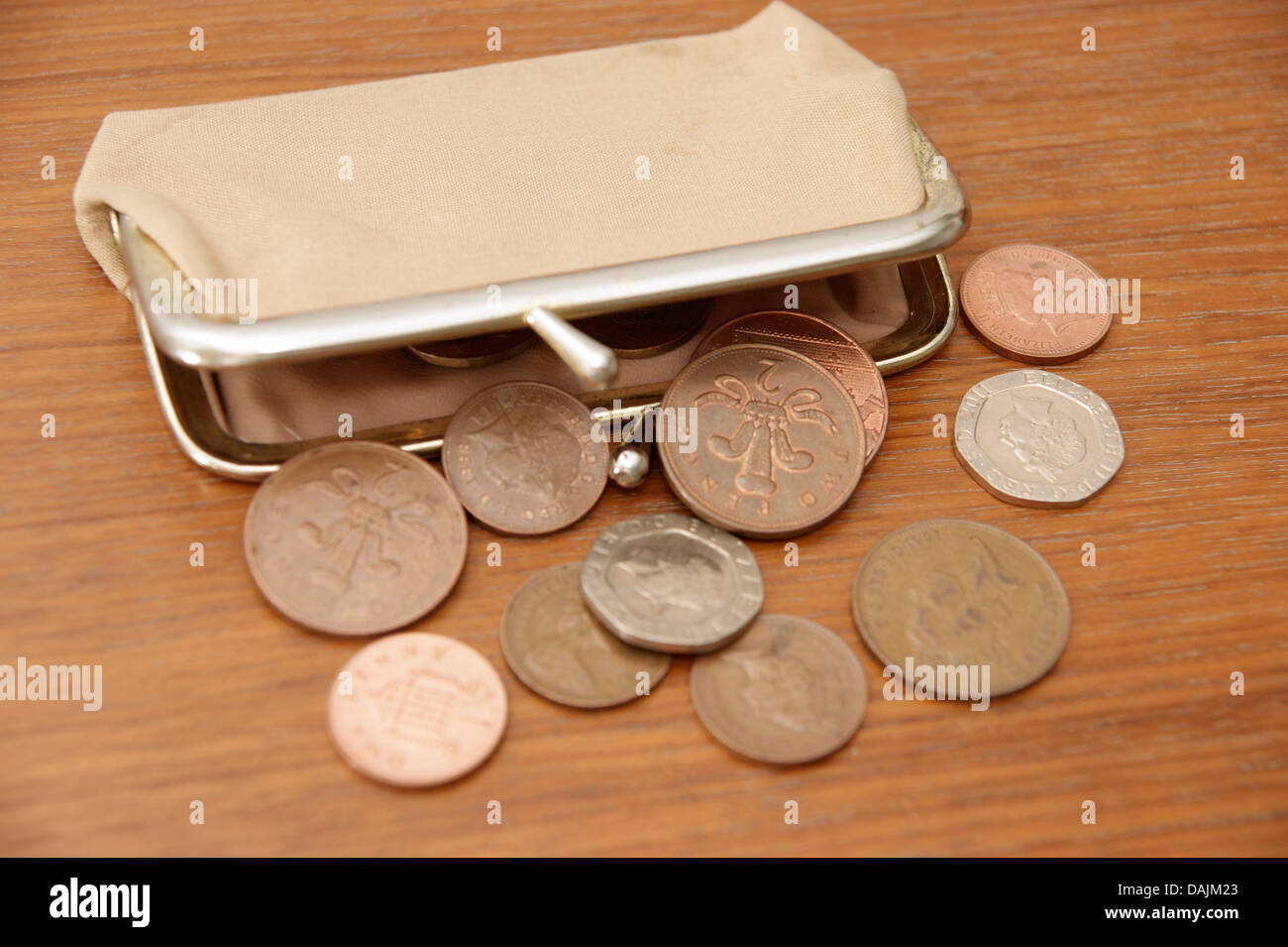 Una bolsa llena de monedas (British sterling dinero) derramándose sobre una mesa Foto de stock