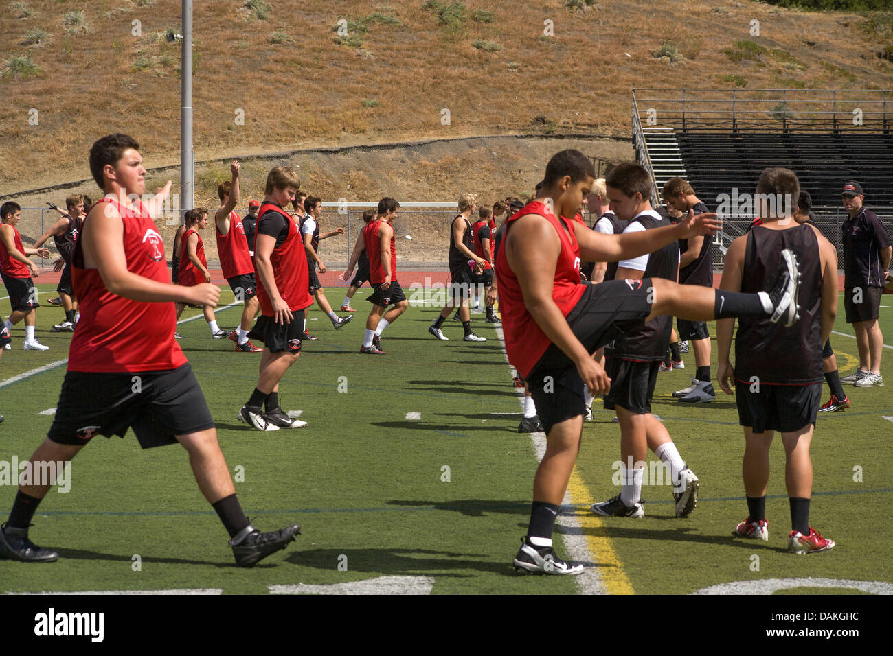 Escuela multiétnica atletas calientan con ejercicios de flexibilidad ya que comienzan la práctica de fútbol de primavera en California. Foto de stock