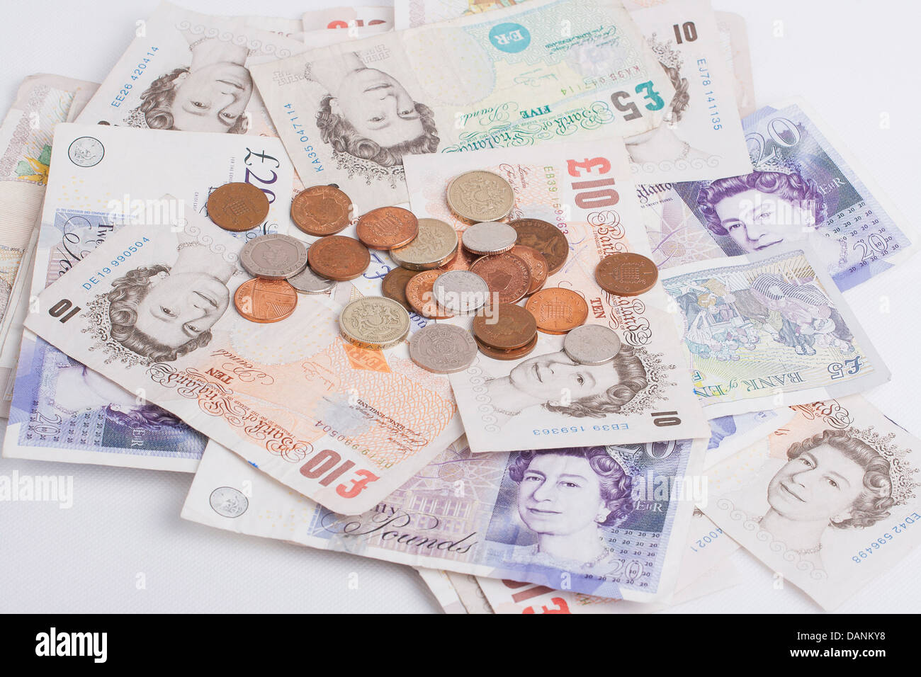Billetes y monedas británicas sobre fondo blanco. Foto de stock