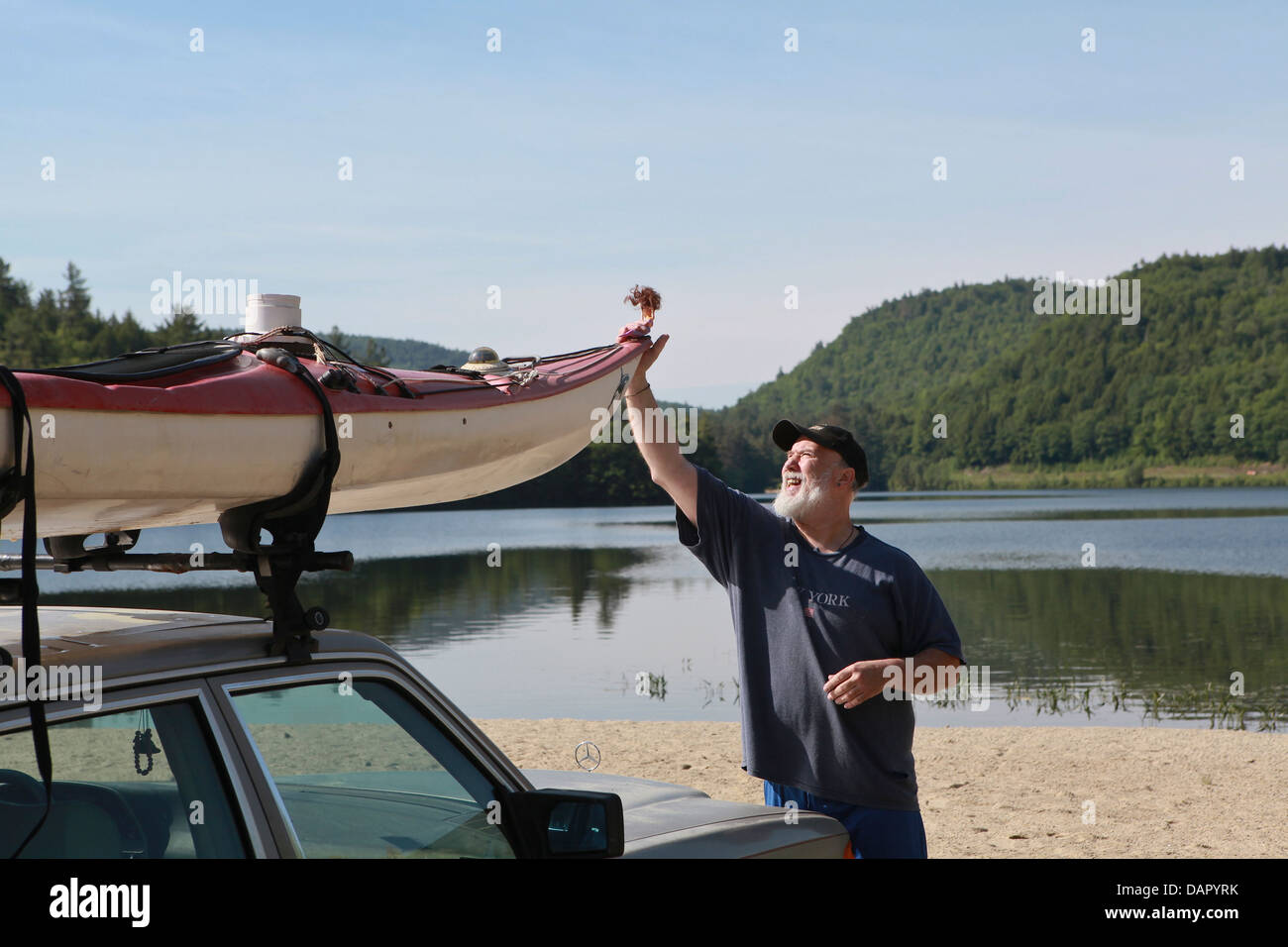 Un hombre asegura su kayak en la parte superior de su coche por el lago Crystal en Eaton, New Hampshire Foto de stock