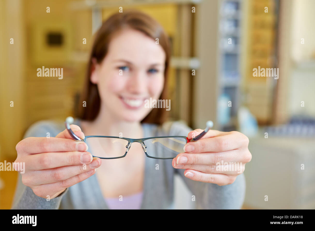 Mujer joven celebrar nuevas gafas en almacén óptico Foto de stock