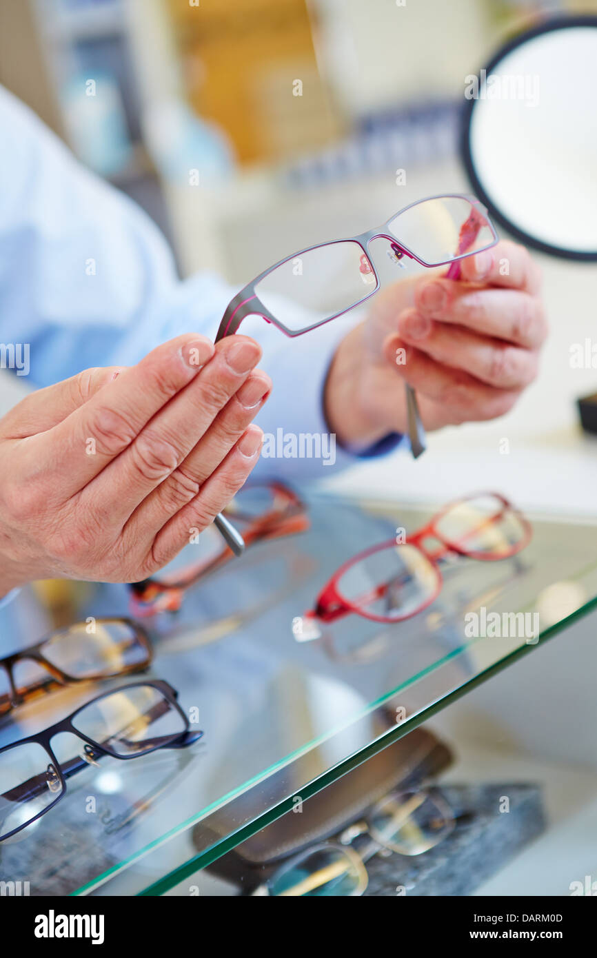 Manos de un óptico ofreciendo nuevas gafas en su tienda minorista Foto de stock