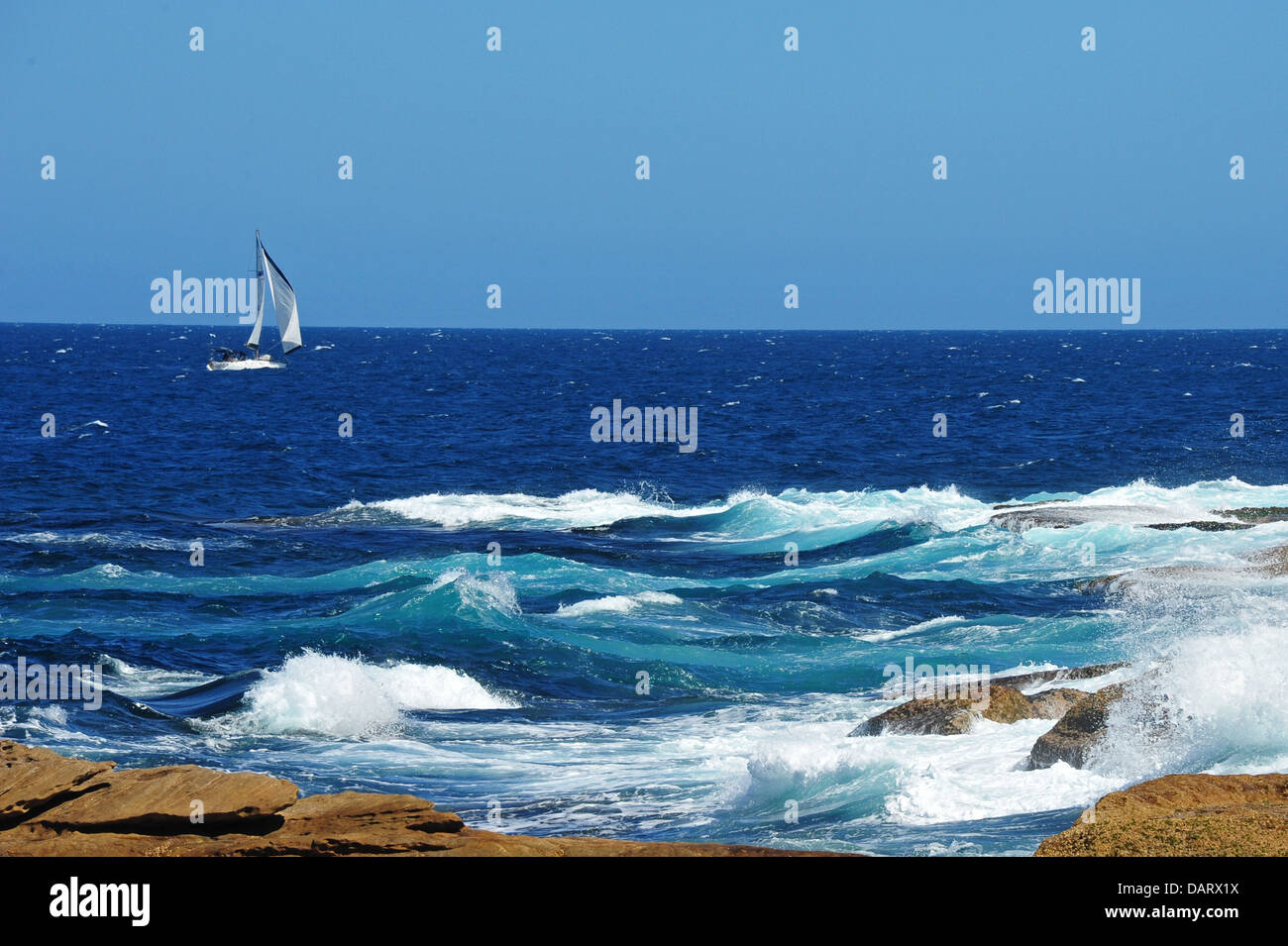 Yate en la costa con mar gruesa Foto de stock