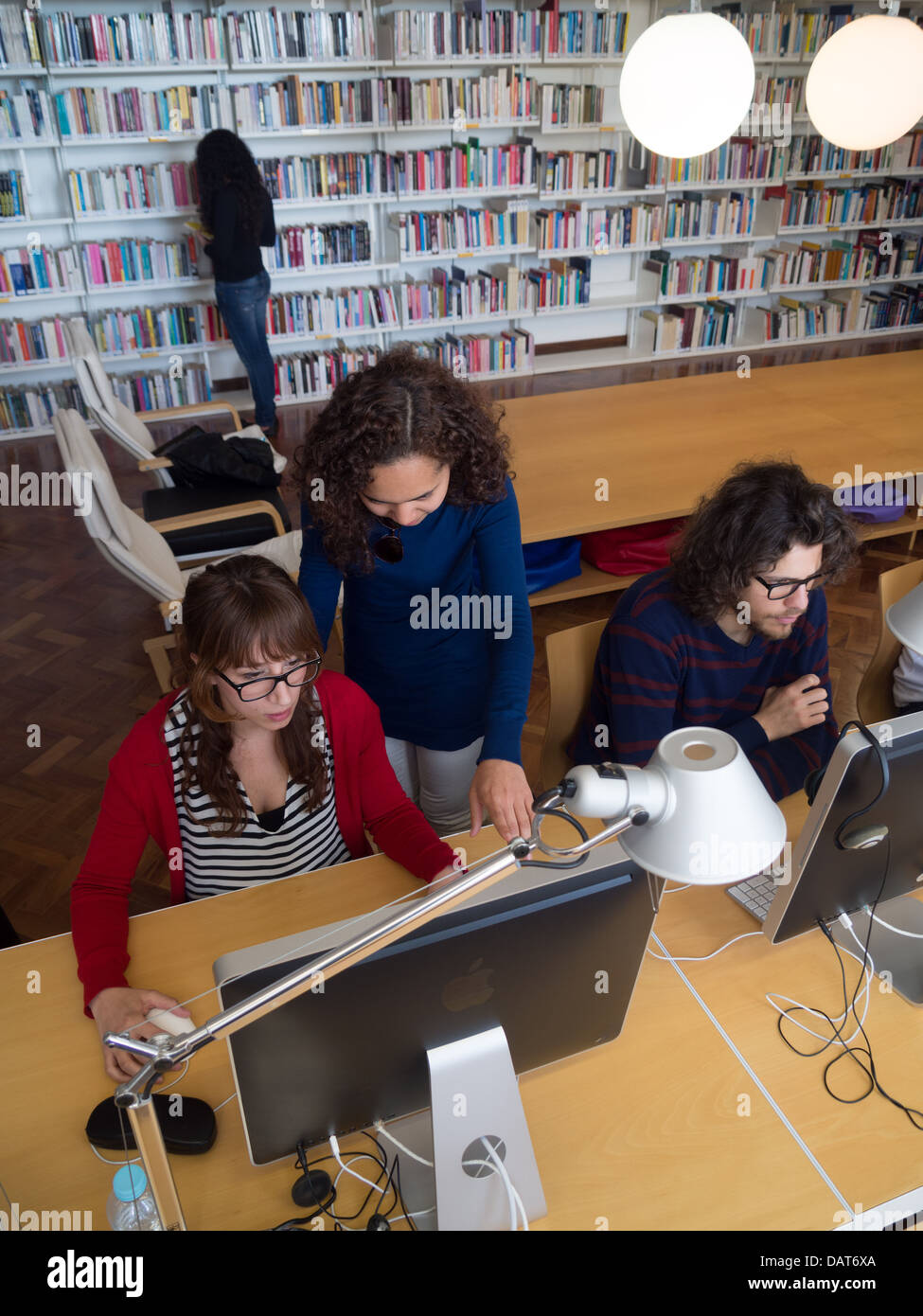 Dos mujeres usando un ordenador Apple iMac en la biblioteca Foto de stock