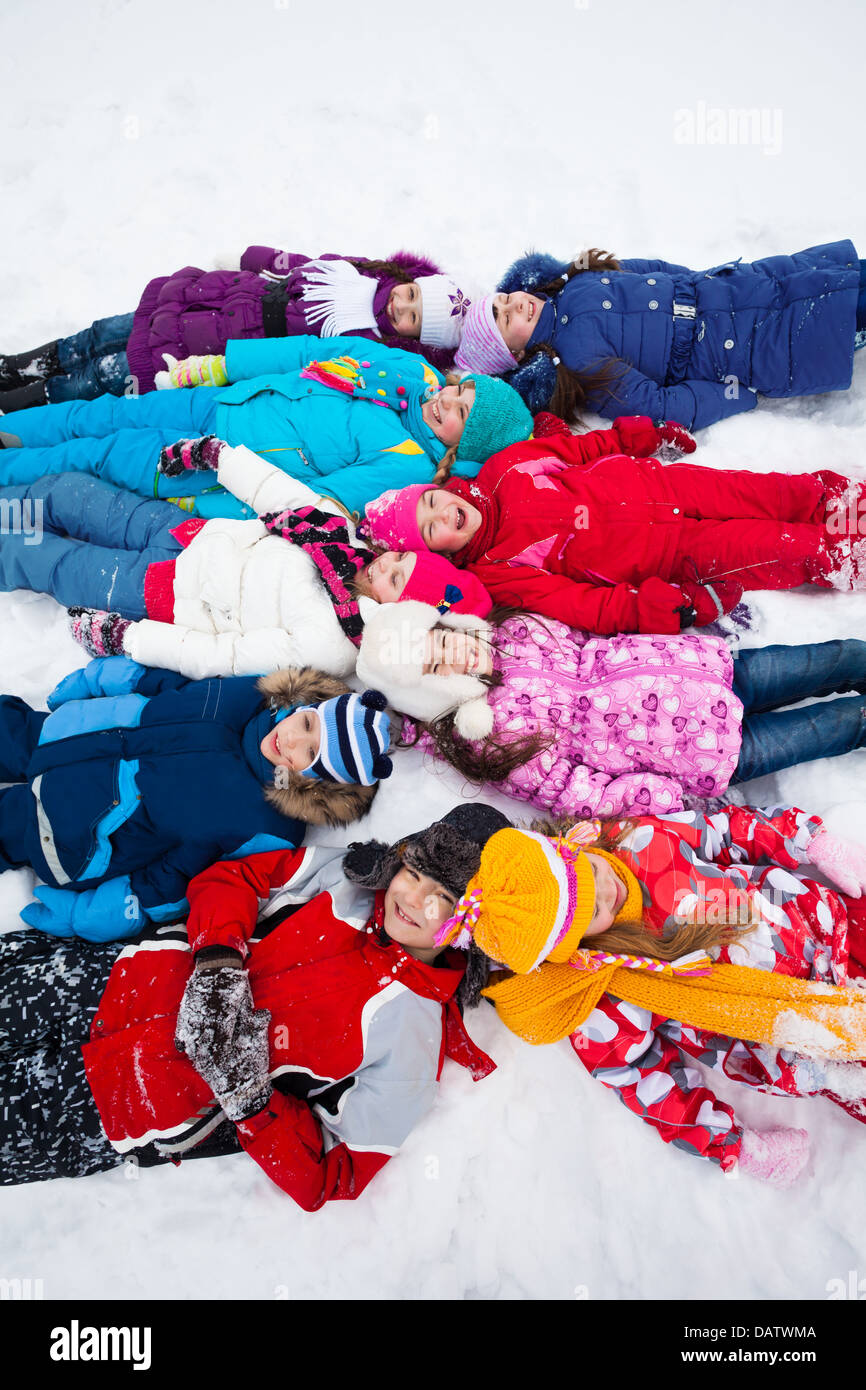 Gran grupo de niños 5-10 tendido en la nieve juntos, vista desde arriba Foto de stock