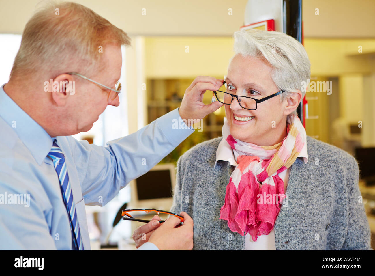 Óptico ofreciéndole asesoramiento a altos para mujer nuevas gafas Foto de stock