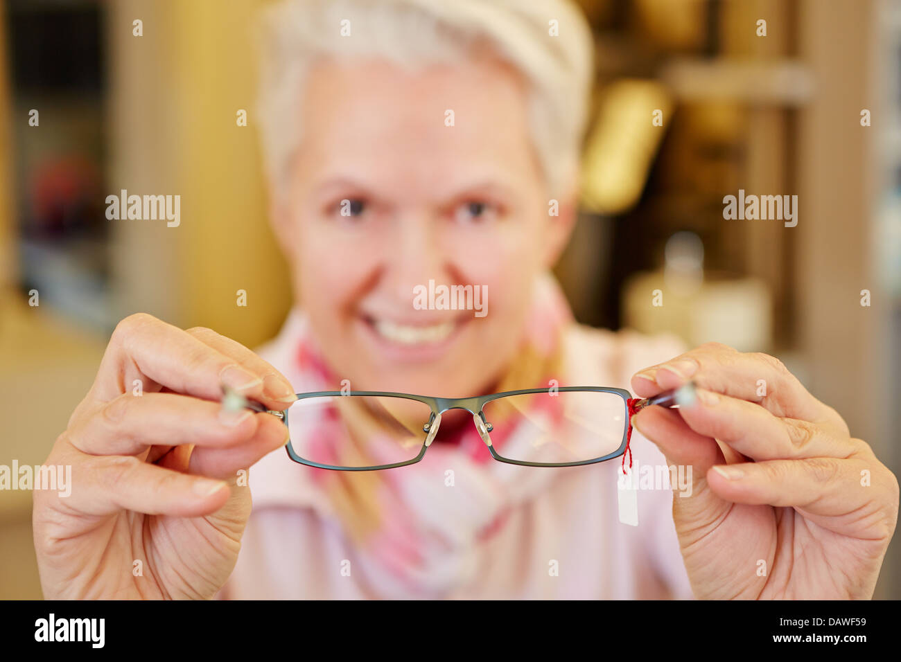 Óptico senior sonriente sosteniendo anteojos nuevos en sus manos Foto de stock